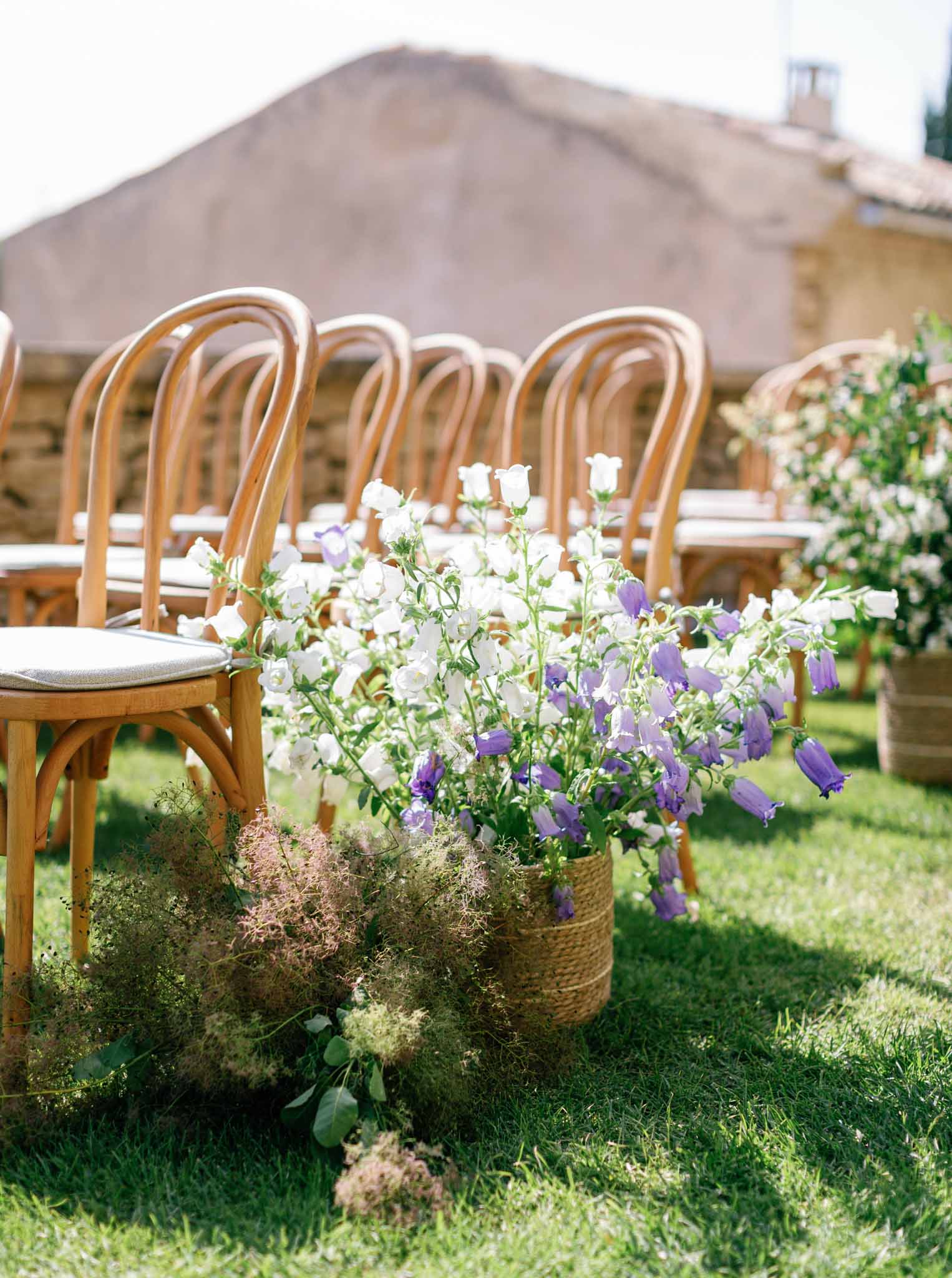 Ground-level view of ceremony aisle with bentwood chairs and white floral arrangements