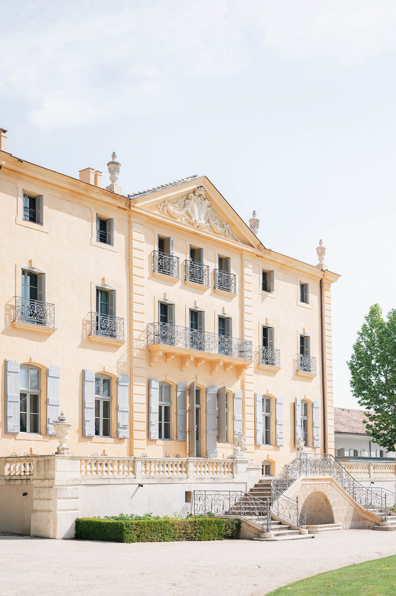 Three-storey peach-toned chateau with wrought-iron balconies stone urns and grand horseshoe staircase