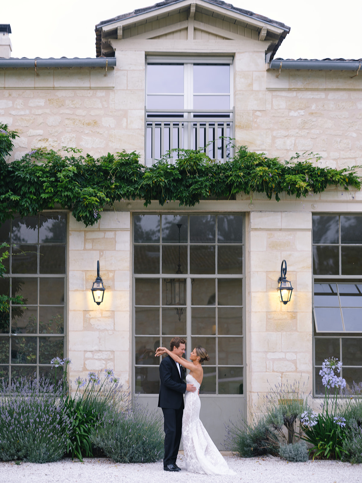 Bride and groom hugging in front of Château Gassies stone facade