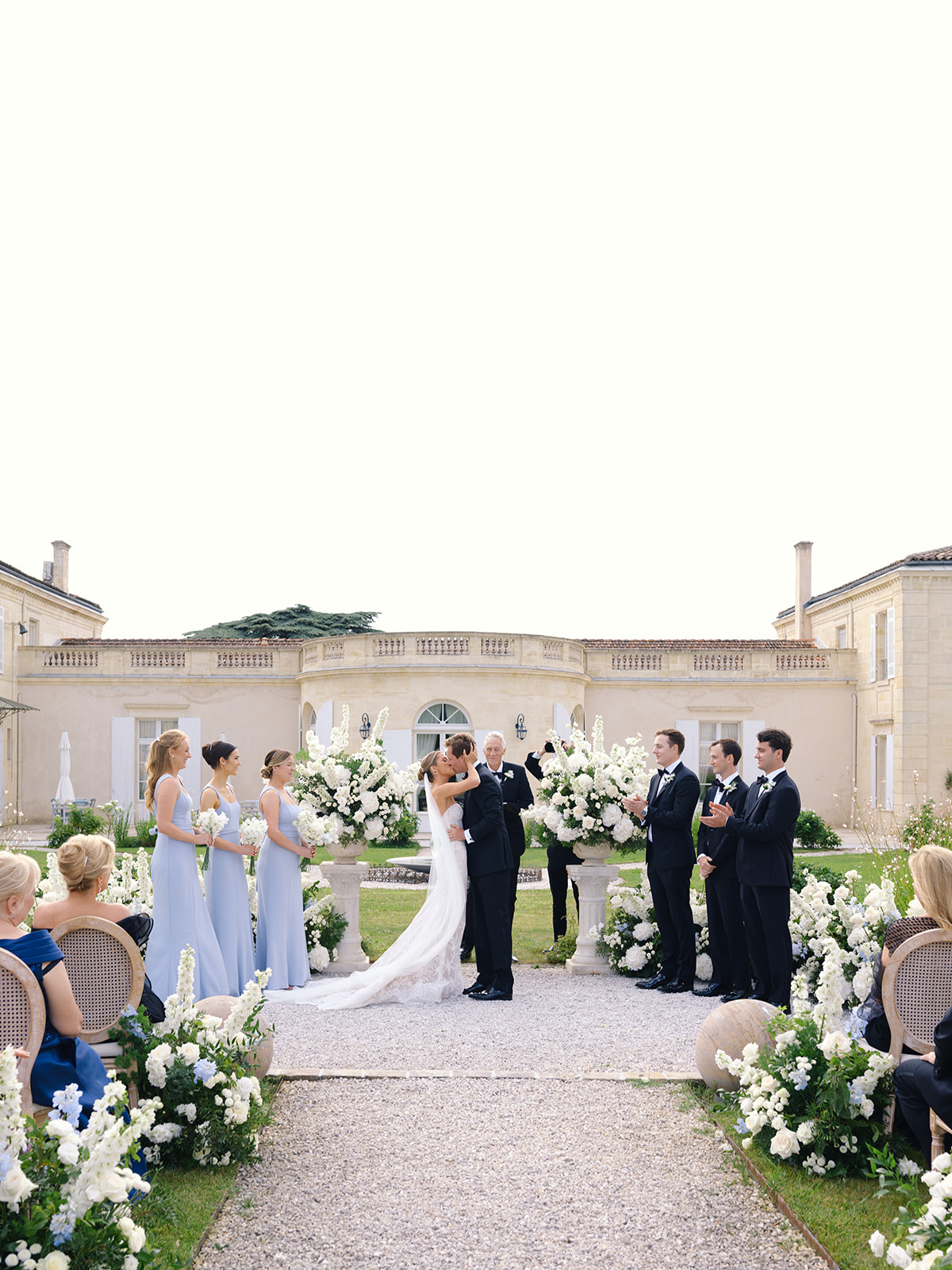 Outdoor ceremony in courtyard of classical manor house with bride and groom at centre
