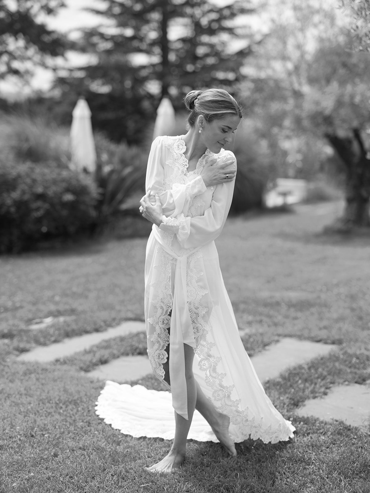 Black and white bridal portrait in garden wearing lace robe with flowing train