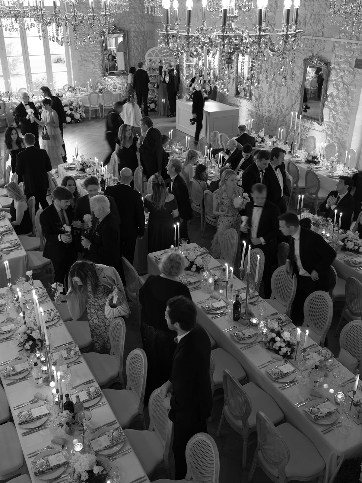 Black and white overhead view of formal ballroom reception, 100+ guests, crystal chandeliers, candelabras, white florals
