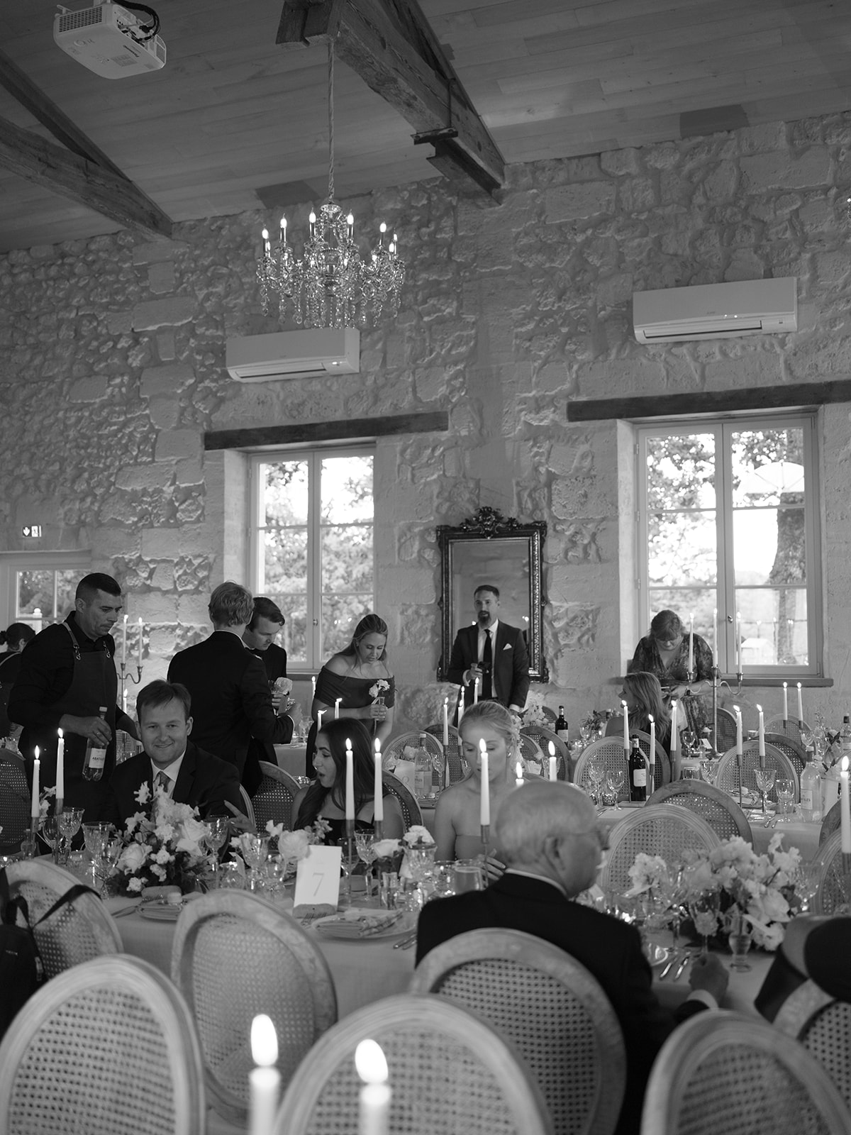 Guests at candlelit reception area at Château Gassies, black and white photograph