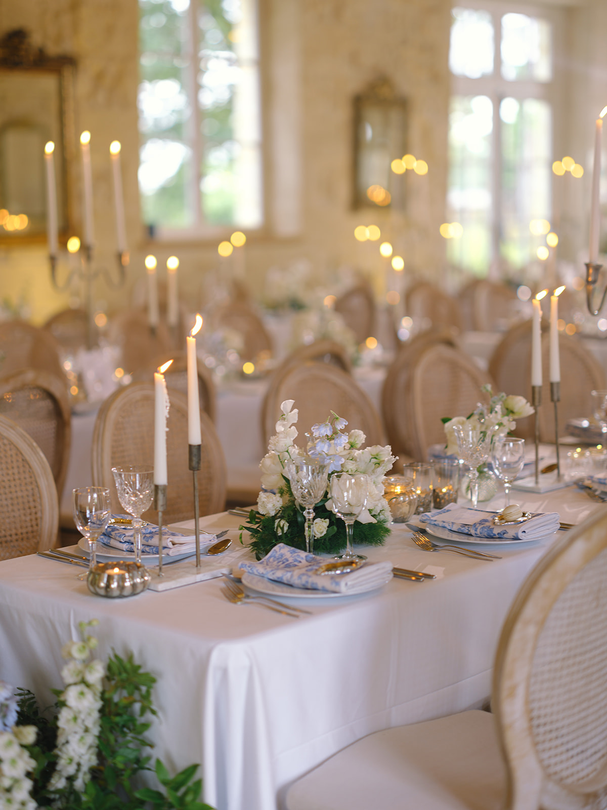 Formal reception table with blue patterned napkins, silver candlesticks, and white floral centerpieces