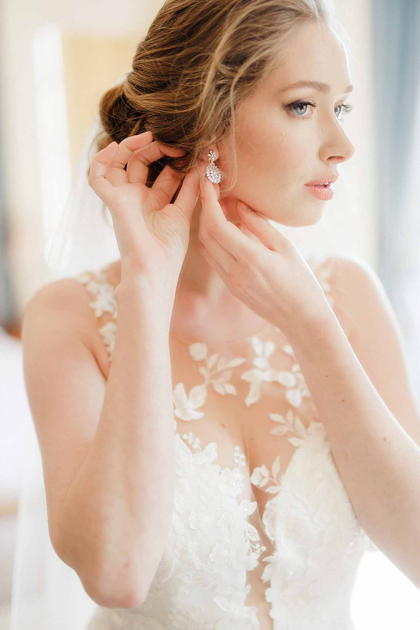 Bride putting on earrings while getting ready at Château de Trieux