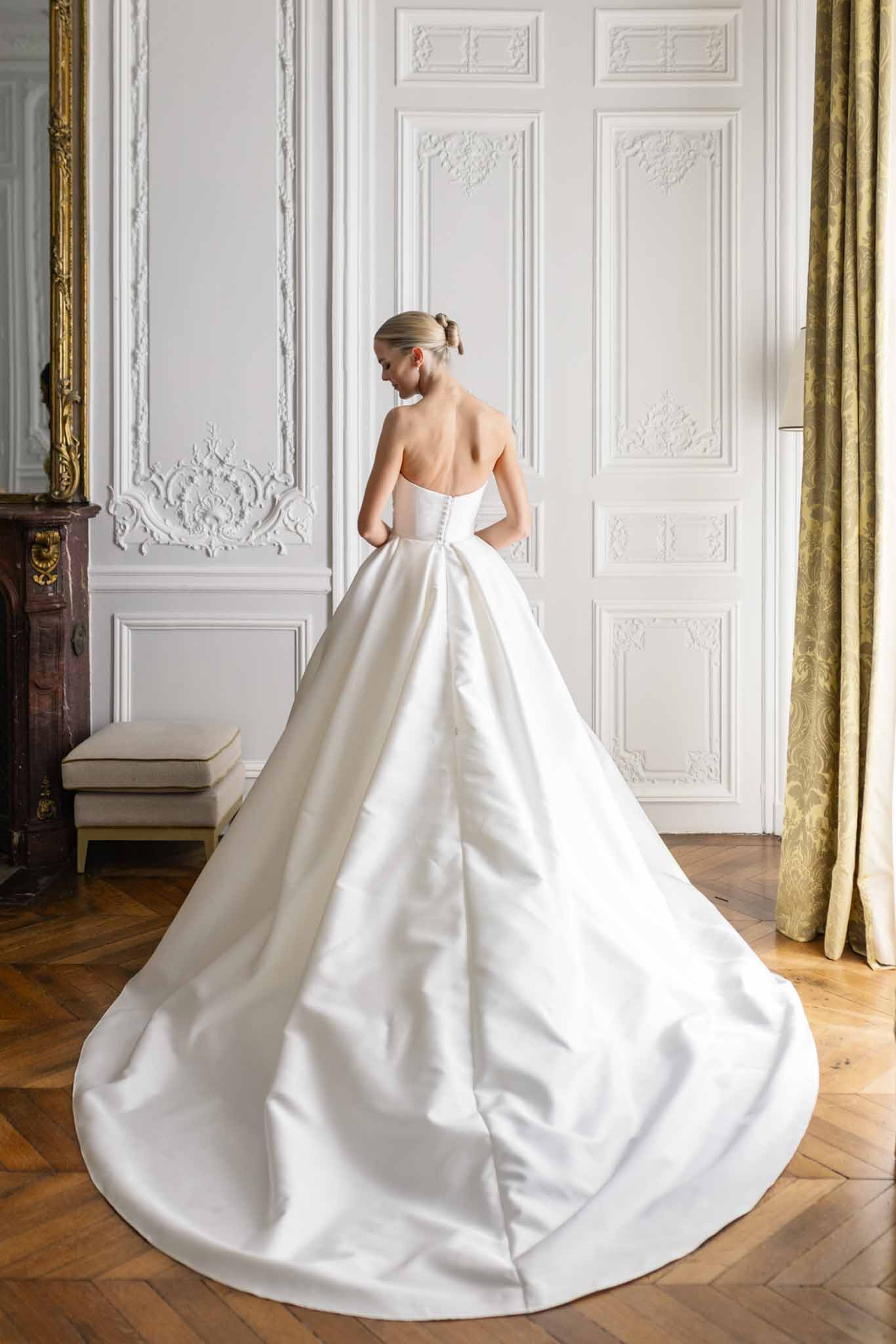 Bride seen from behind wearing ivory strapless ball gown with cathedral train in neoclassical gilded interior