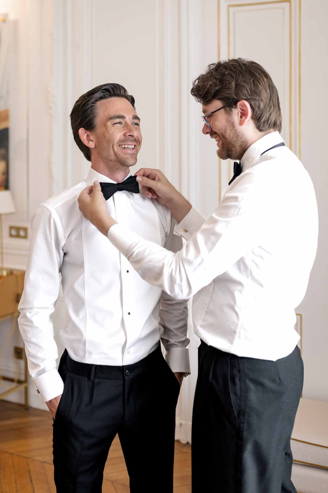 Groom and best man fixing bow tie while getting ready at Villette Dream Paris wedding