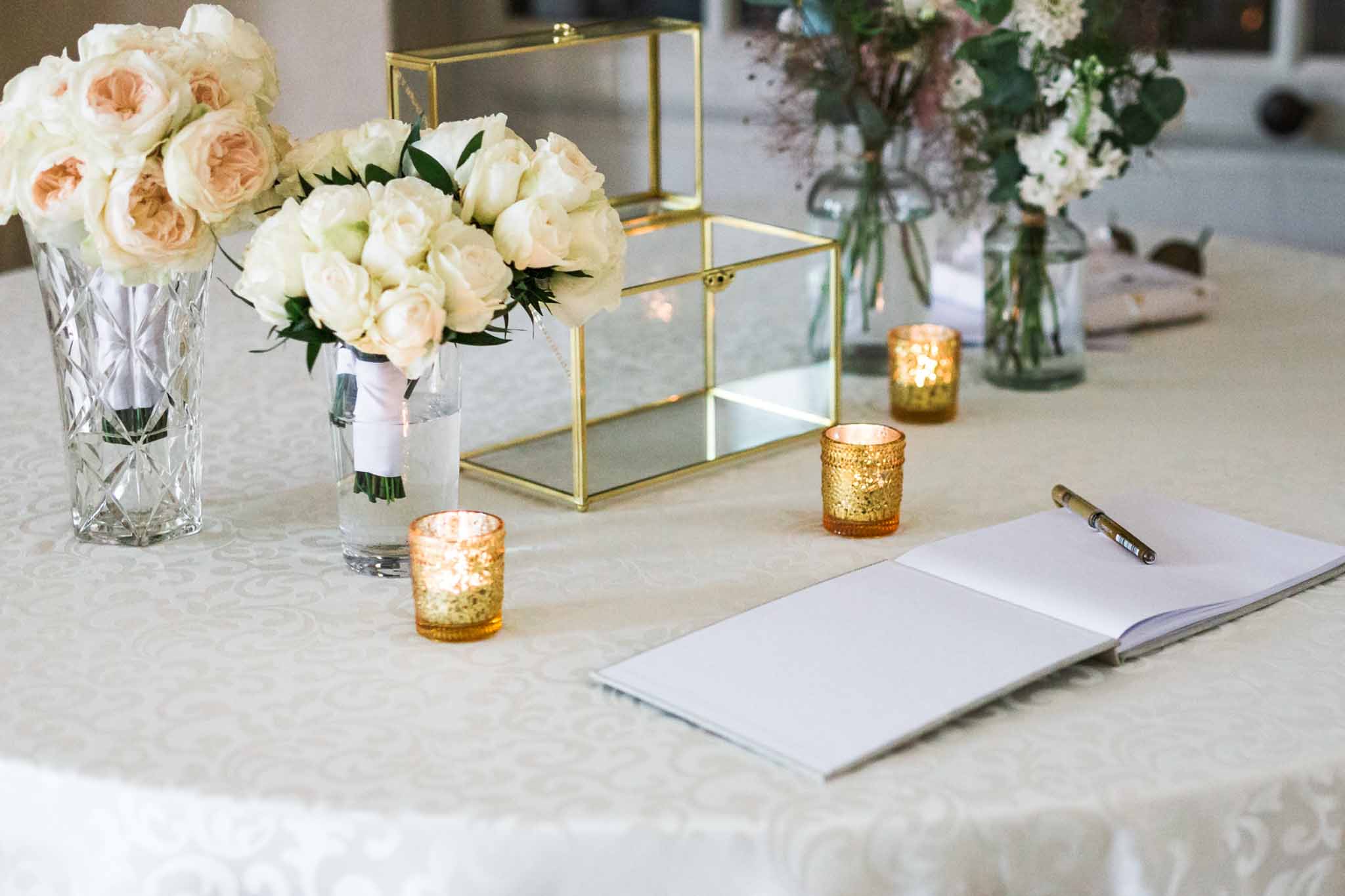 Guests at ceremony registry table with flowers in vase and candles at Château de Villette, Paris