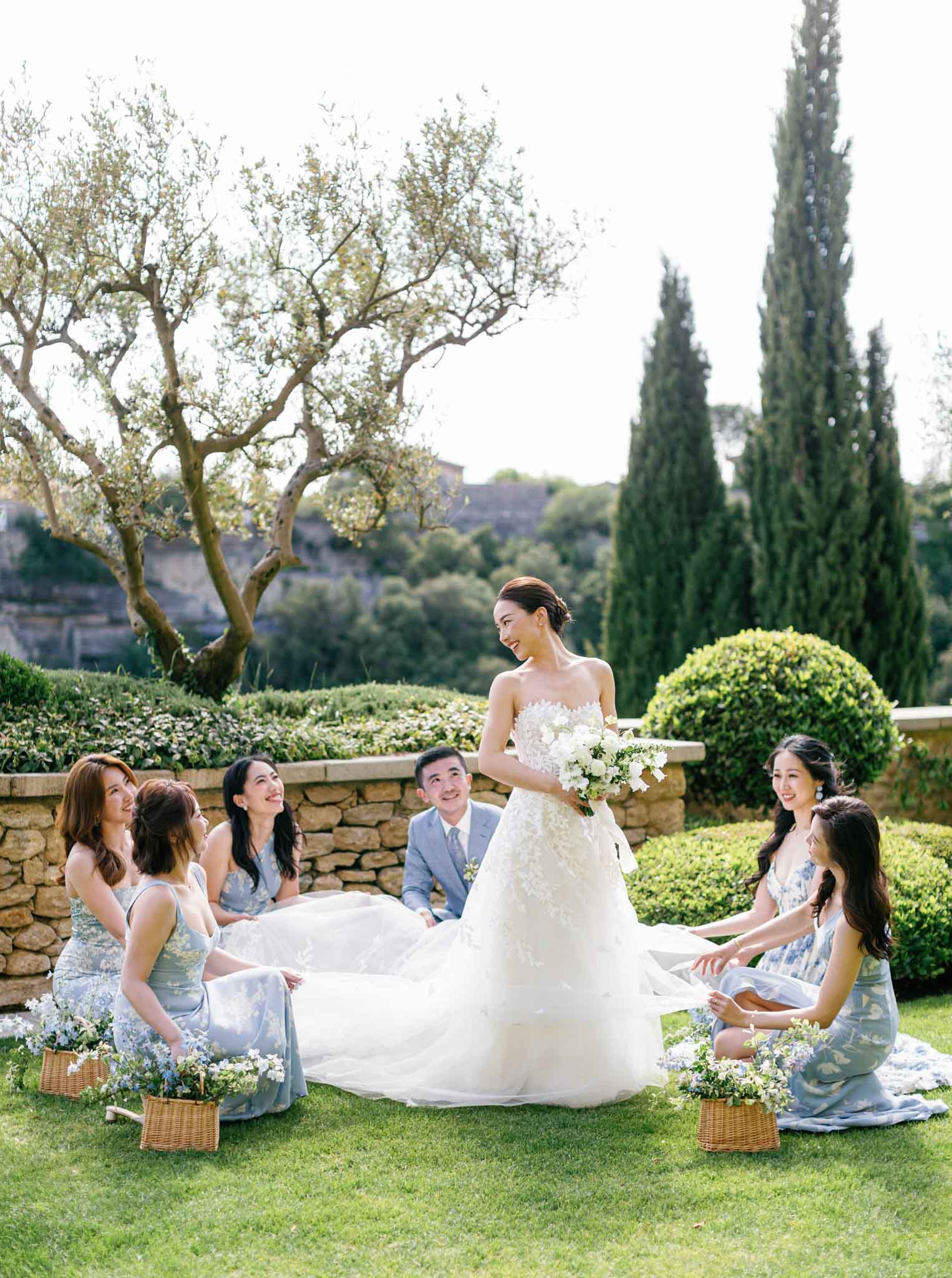 Bride and bridal party seated on lawn with cypress trees and Provencal hillside backdrop