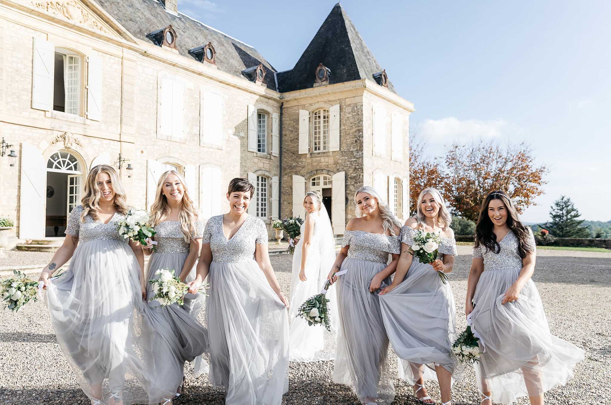 Six bridesmaids in silver-grey sequined tulle gowns walking toward camera with bride behind