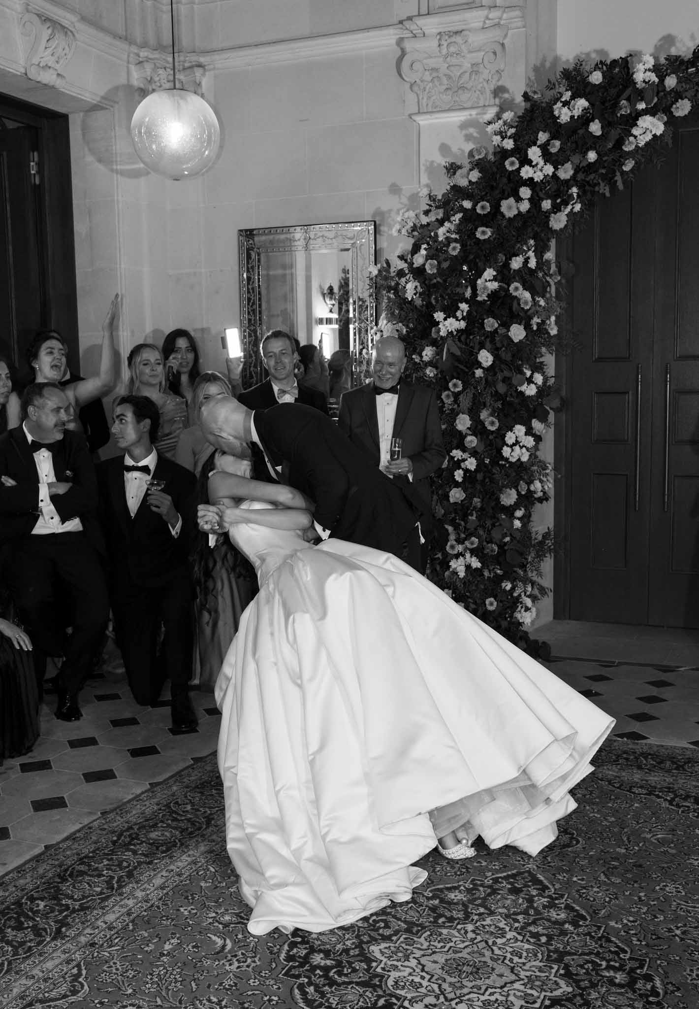 Black-and-white first dance with dramatic white floral wall installation in neoclassical ballroom