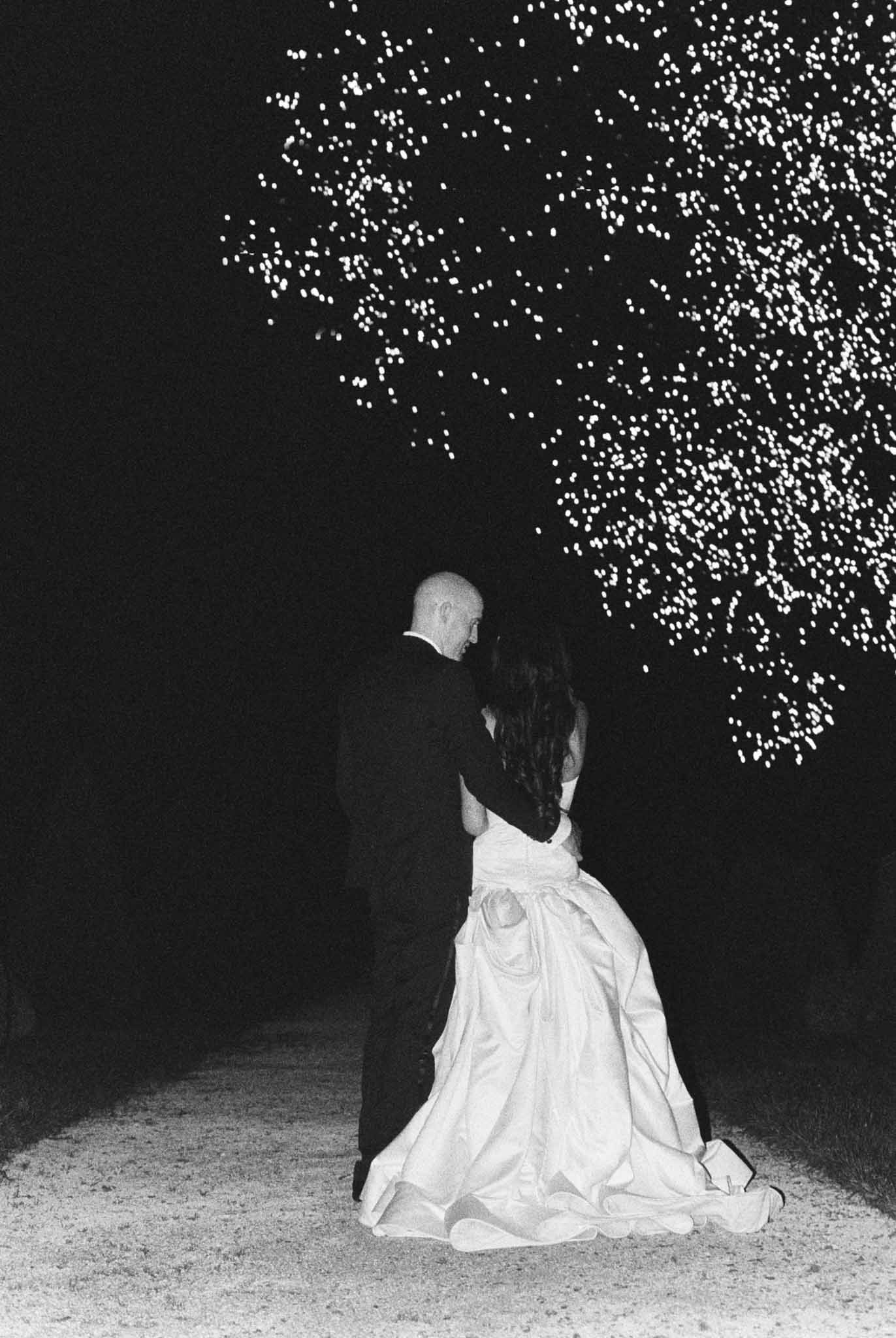 Black and white photo of couple standing beneath cascading light installation at night