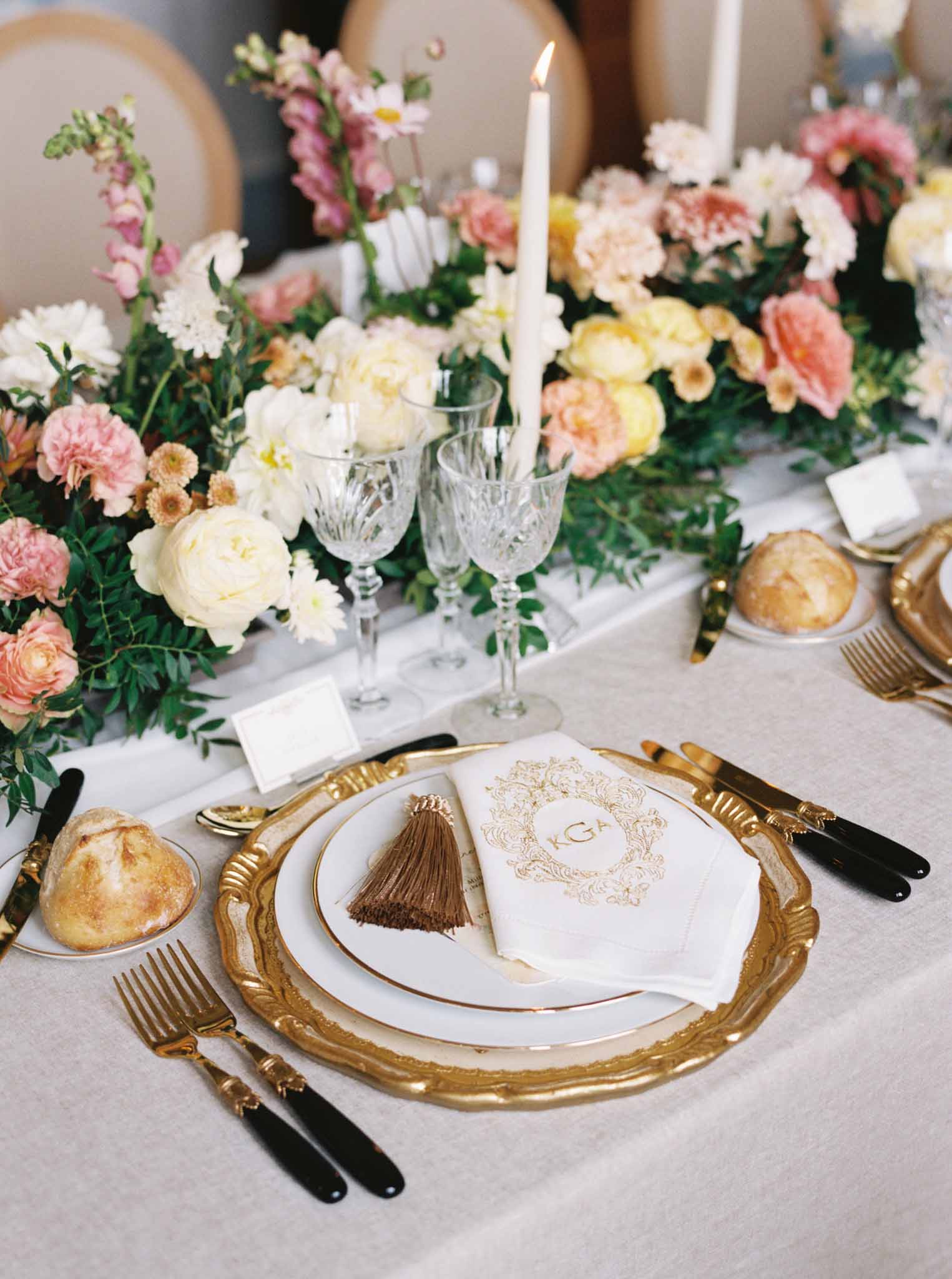 Reception place setting with gold charger, black flatware, cream and coral floral runner and monogrammed menu card