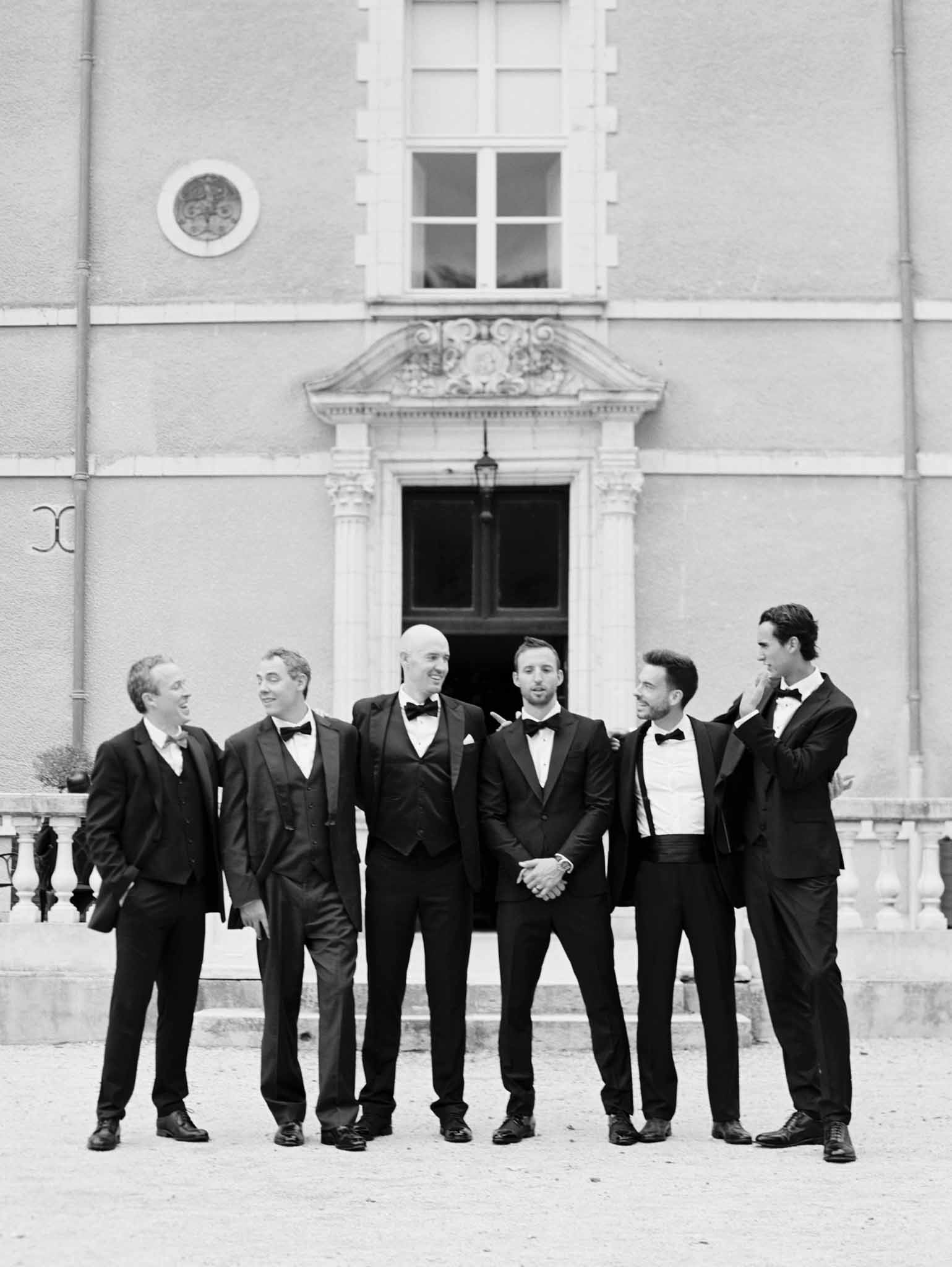Black and white portrait of groom and five groomsmen in tuxedos before neoclassical portico