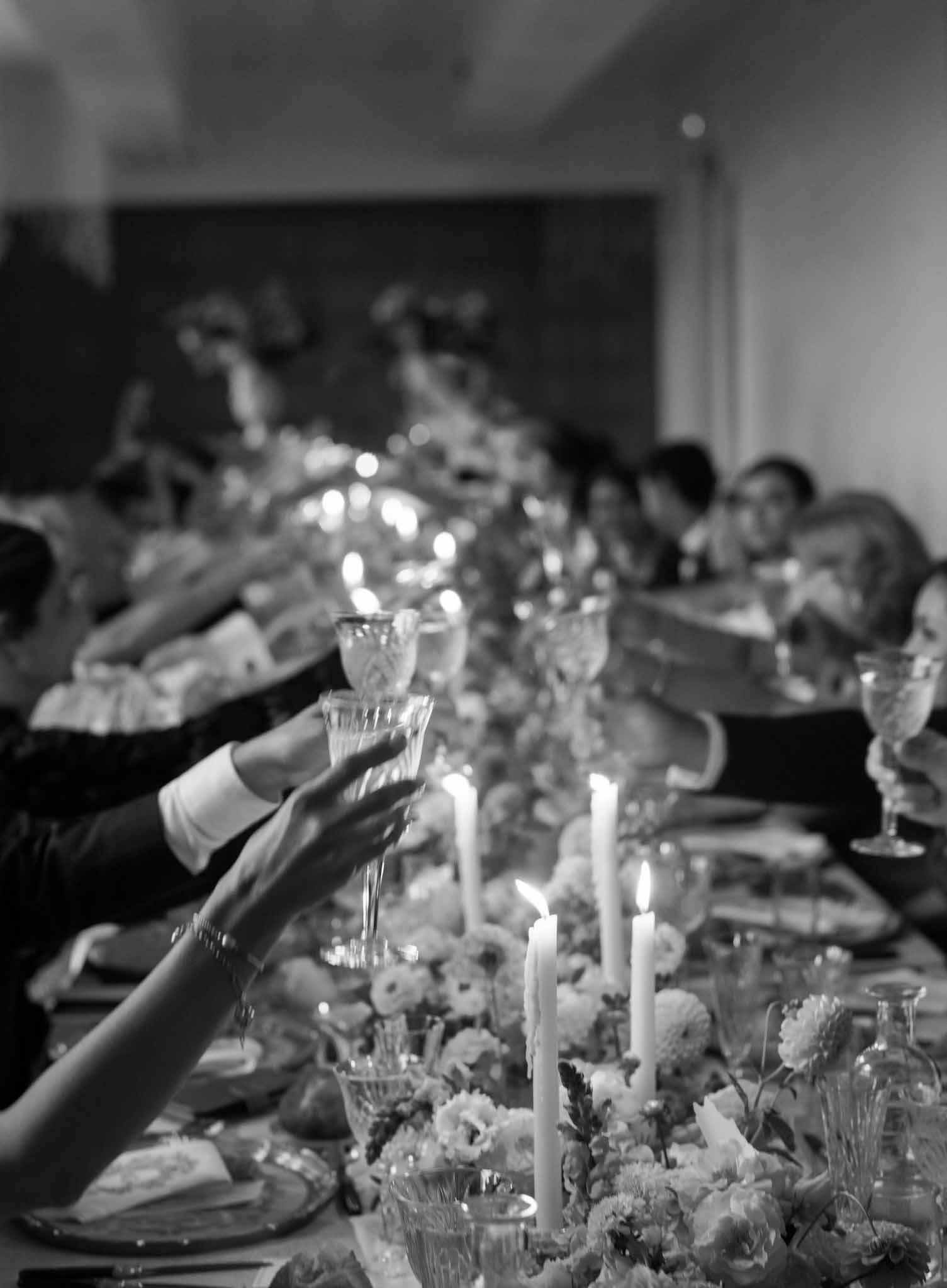 Black and white photo of candlelit reception table with peony centerpieces and crystal glassware