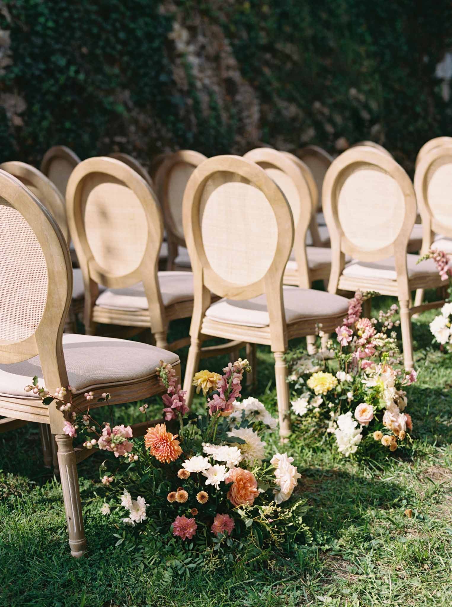 Round wooden ceremony chairs arranged in rows outdoors at Château de Jalesnes