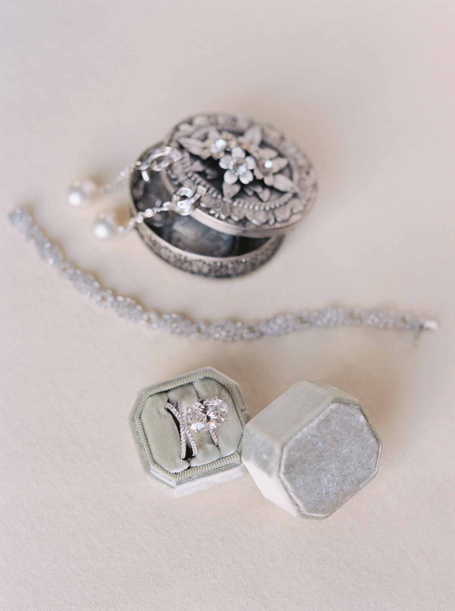 Close-up flat lay of silver wedding bands with filigree and cushion-cut diamond engagement ring