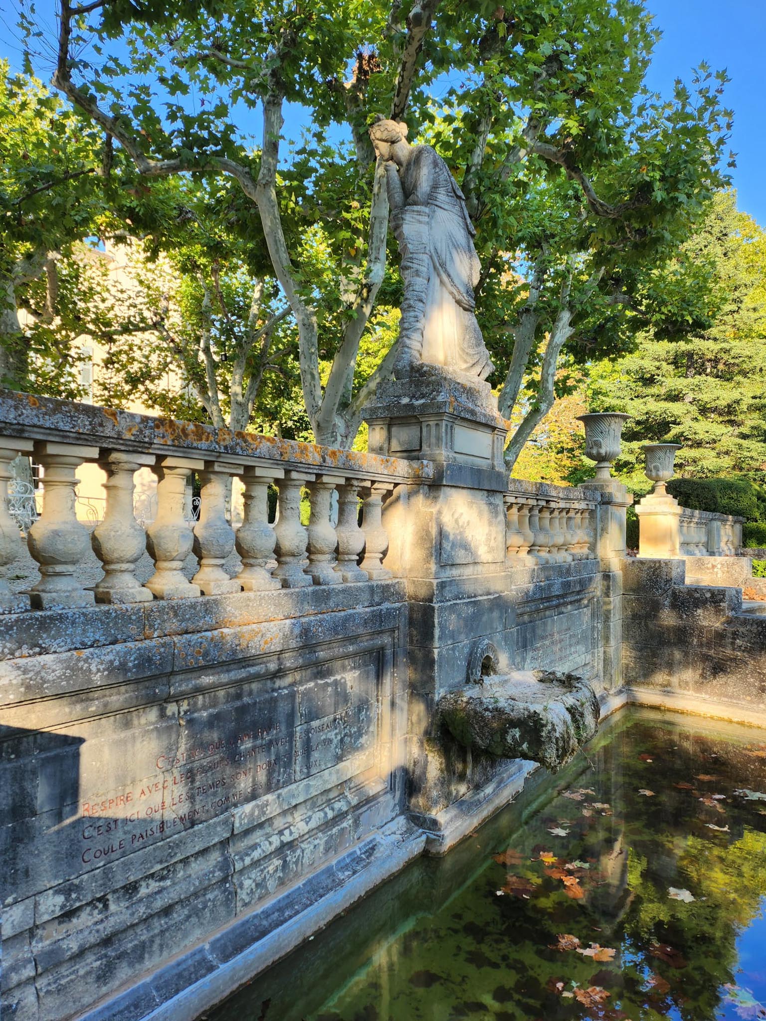 Stone balustrade with classical statue and reflecting pool in autumn at French chateau garden