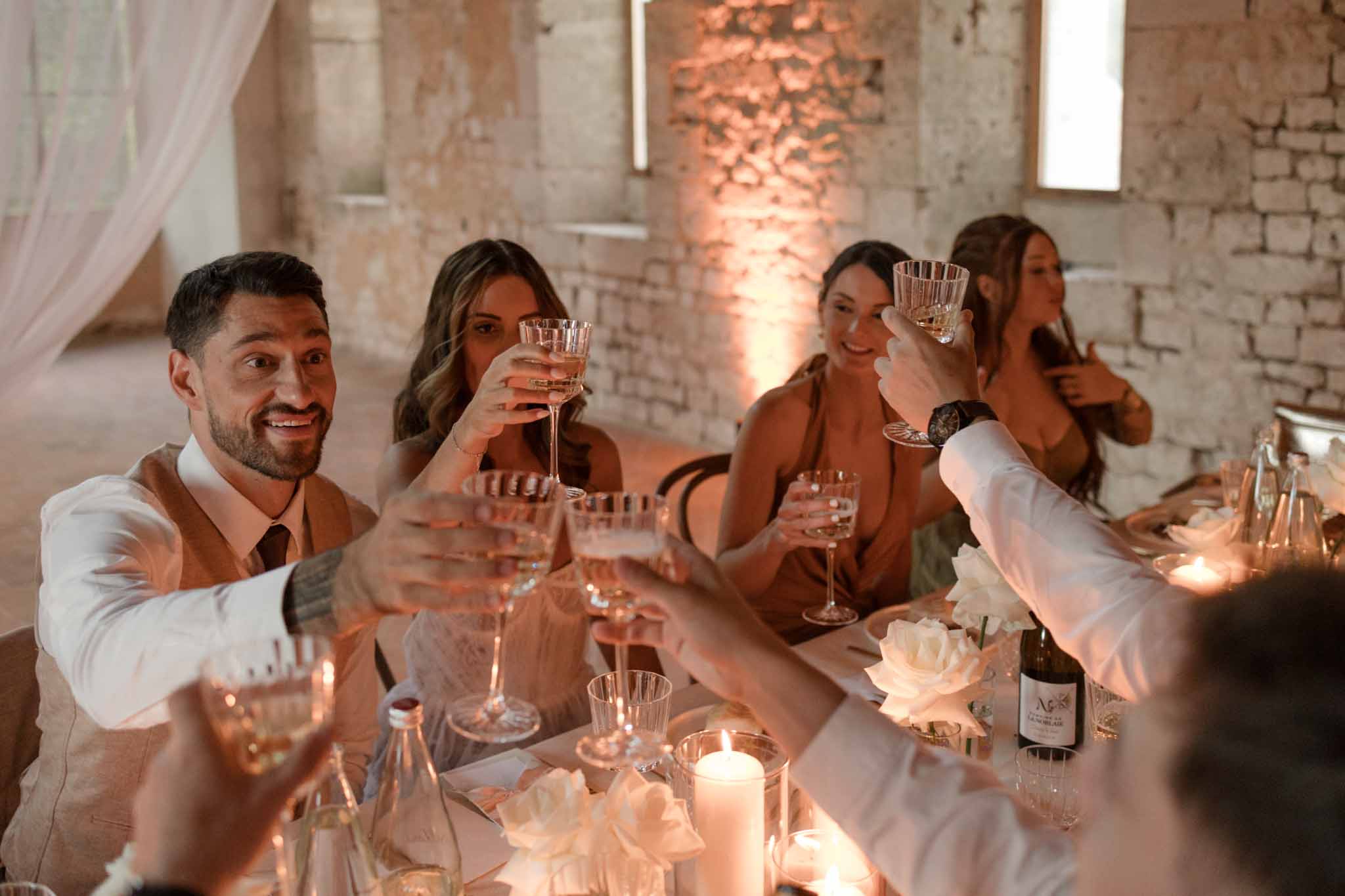 Guests raising glasses for reception toast in industrial brick venue