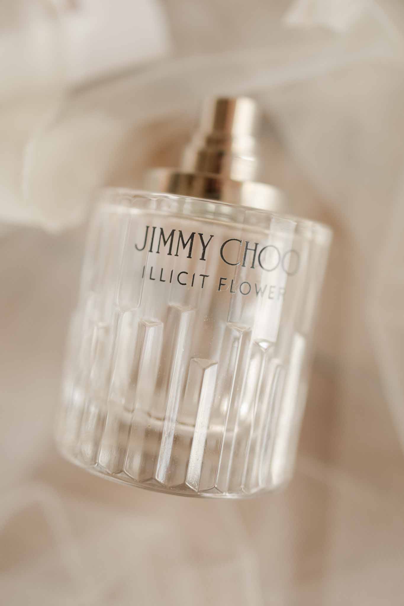 Jimmy Choo Illicit Flower perfume bottle on neutral cream background, shallow focus, label clearly visible