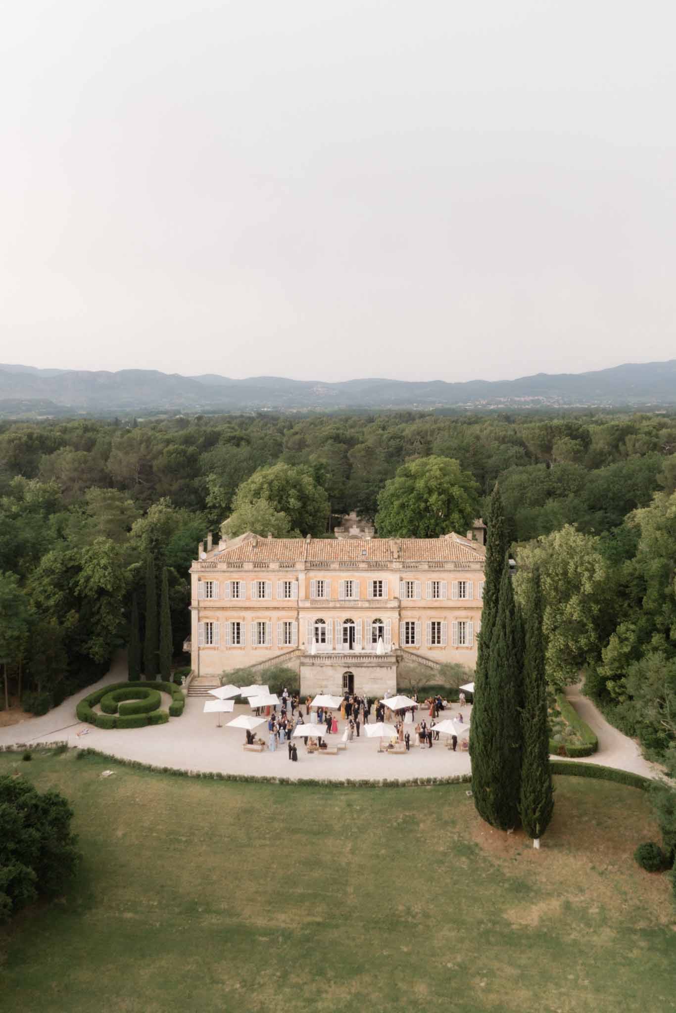 Aerial view of cocktail hour with white tents on Renaissance villa courtyard with cypress trees