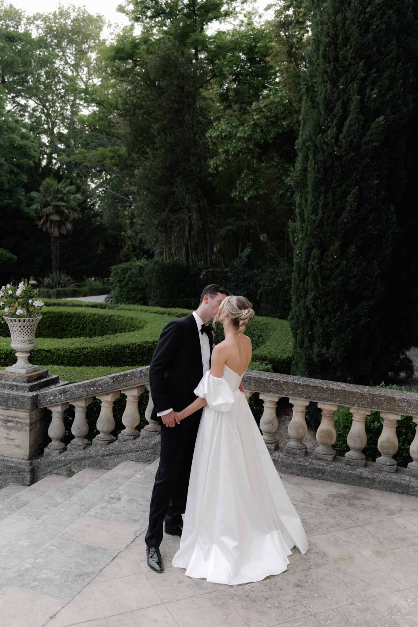 Bride and groom kissing against landscape backdrop at Chateau de Martinay photographed by Despinoy