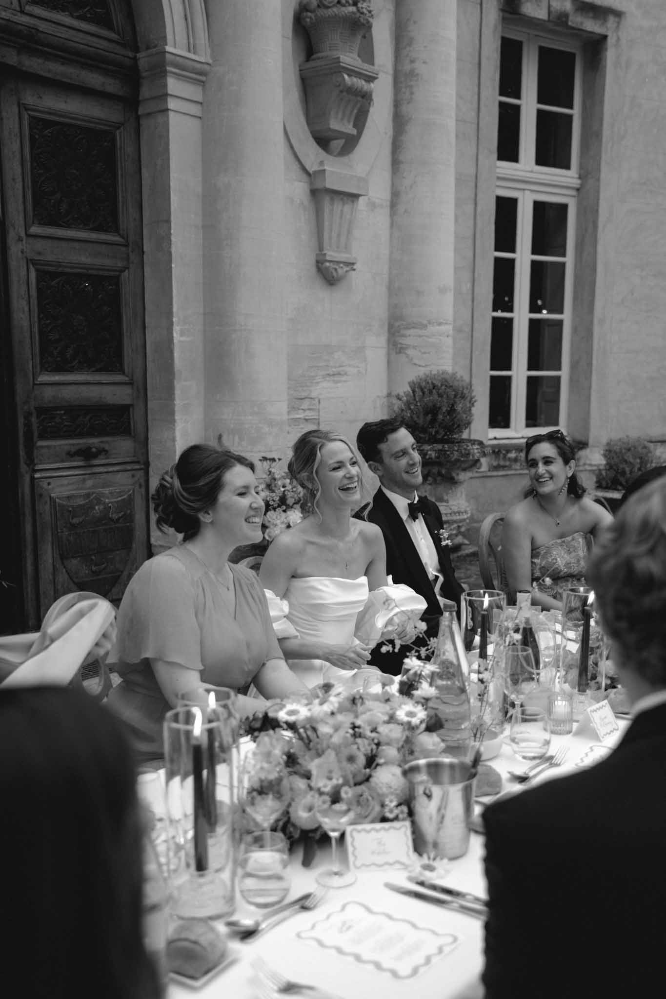 Black and white reception scene with bride and groom at head table before classical stone facade