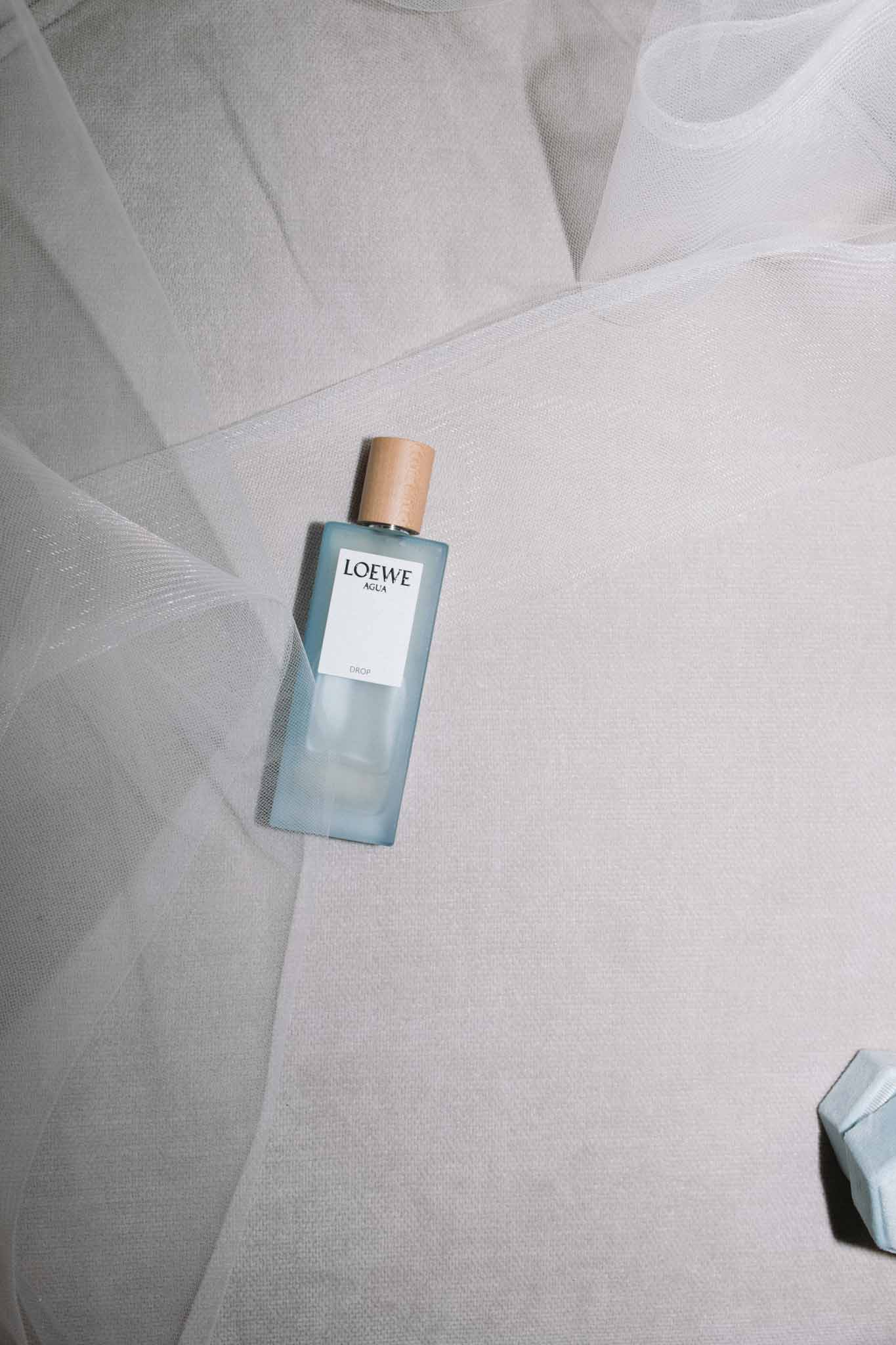 Loewe Agua fragrance bottle with gold cap on ivory tulle fabric, getting-ready detail shot