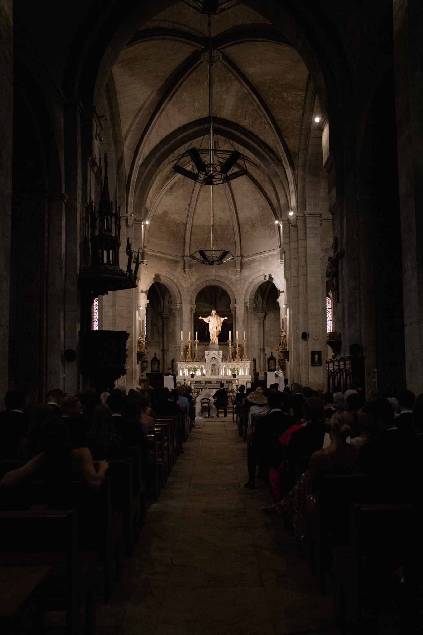 Wedding ceremony in a Gothic stone chapel with vaulted ceiling, stained glass windows, and candlelit altar