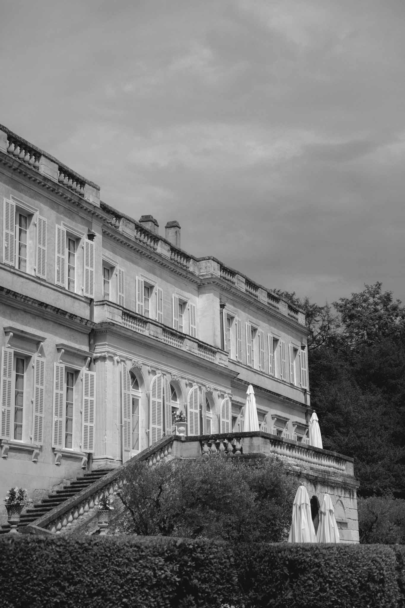 Black and white exterior of French chateau with symmetrical facade and two silhouetted figures on terrace