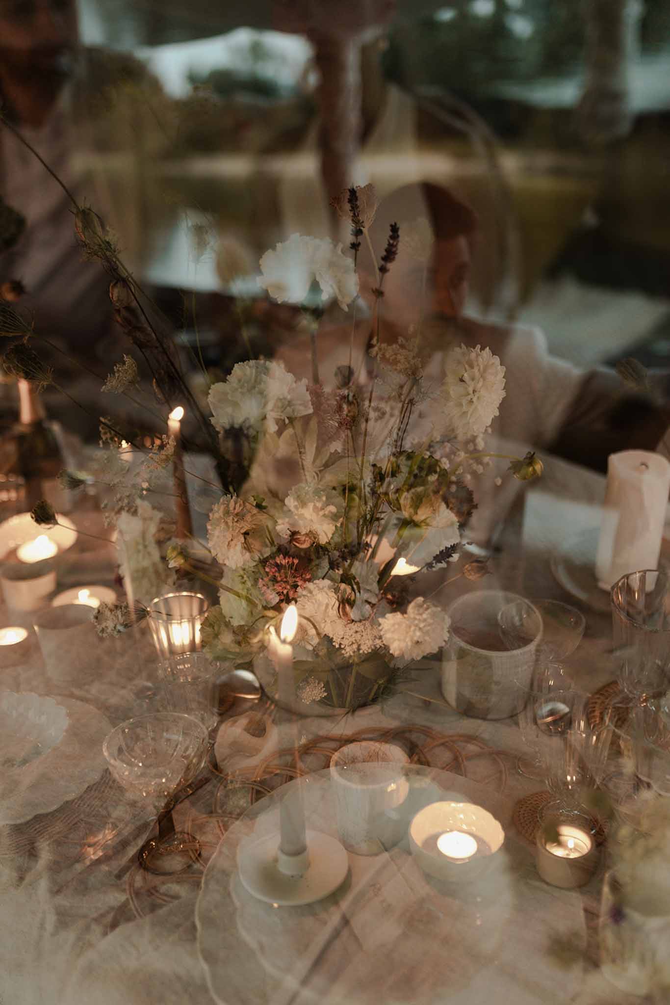 Reception centerpiece with white carnations, dried lavender, and tealight candles in frosted glass holders