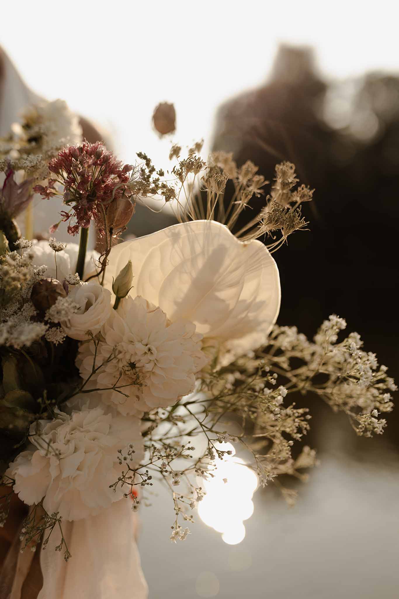 Bridal bouquet of ivory garden roses and calla lilies with burgundy dried astilbe and textured grasses