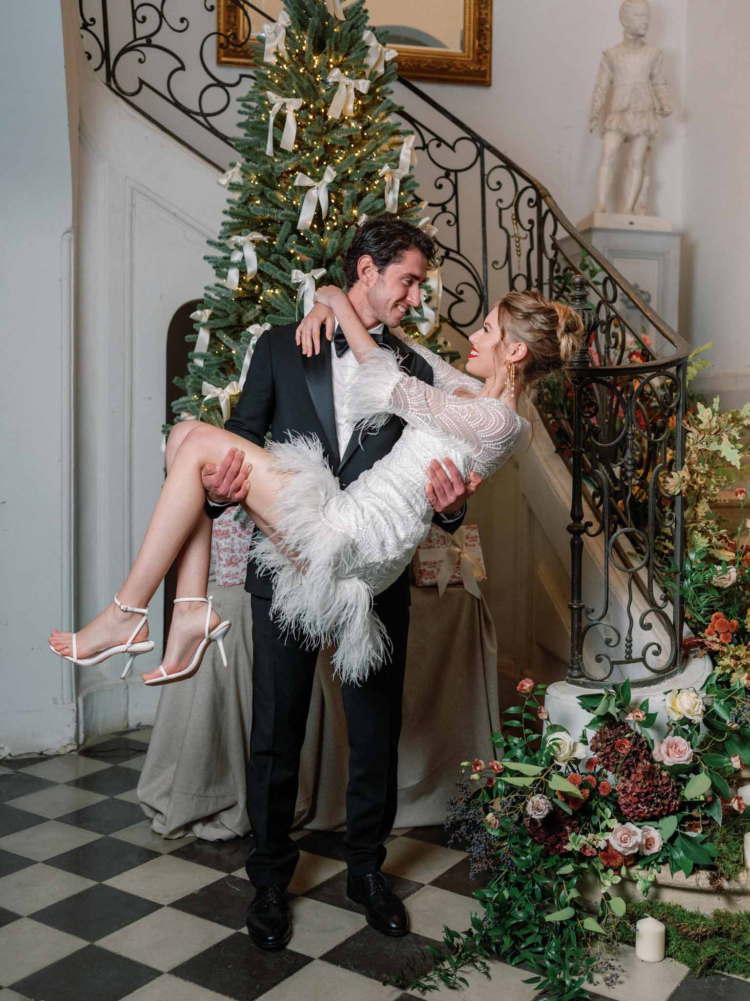 Bride and groom posing beside a vintage car at their wedding