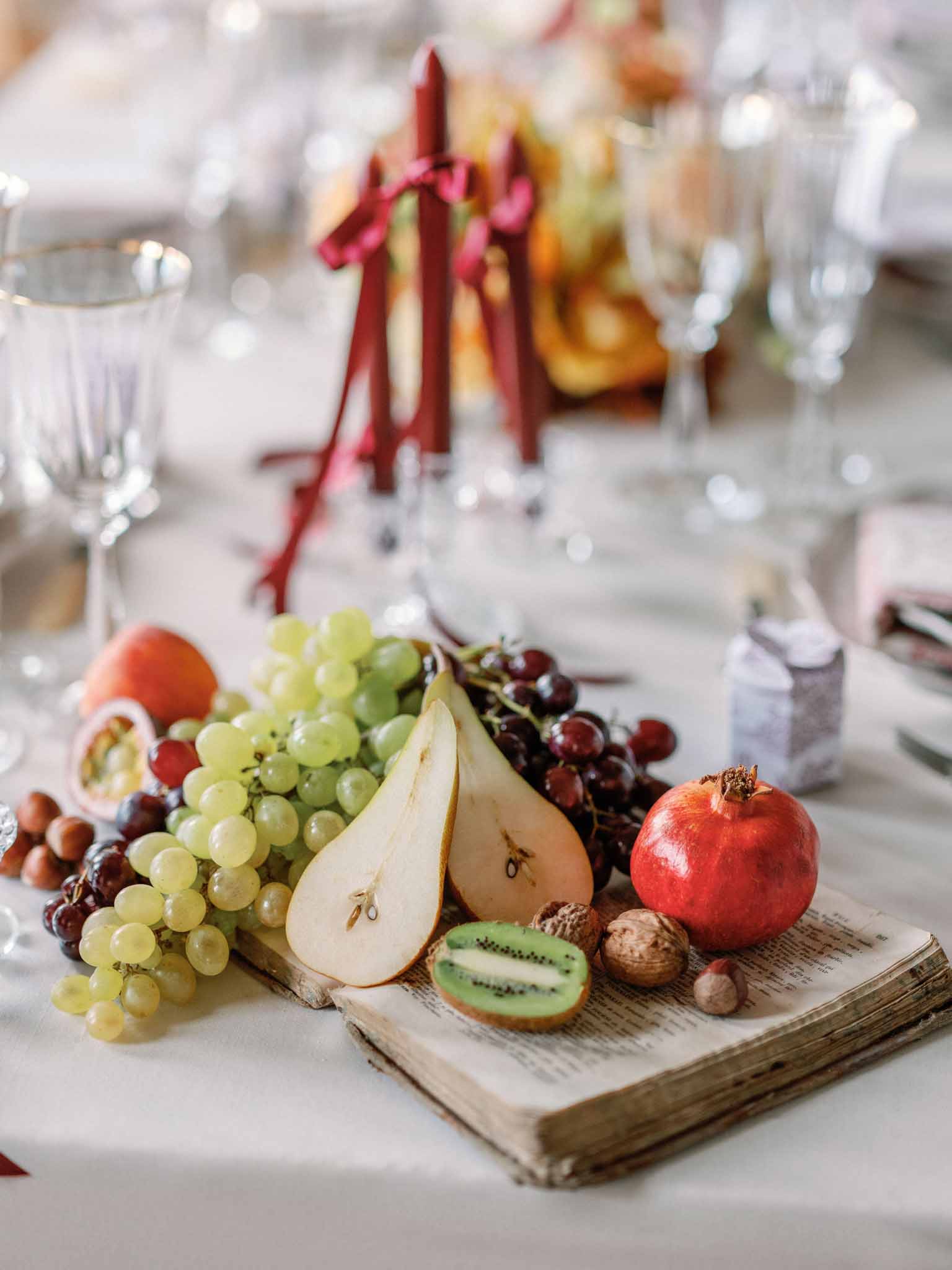 Reception table detail with vintage book and mixed fruit decoration at Chateau Marcellus by Q H Quinze