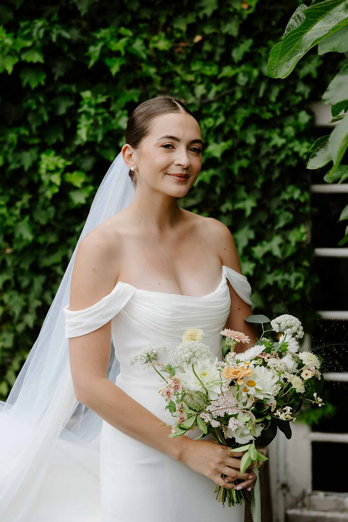 Bride posing with her flowing veil at the wedding venue