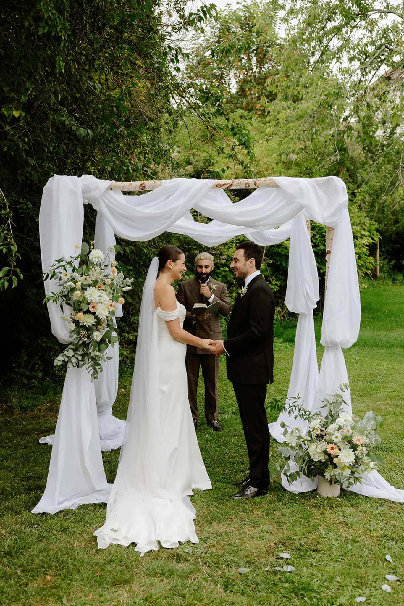 Bride groom and officiant at outdoor ceremony arch at Dîme de Giverny