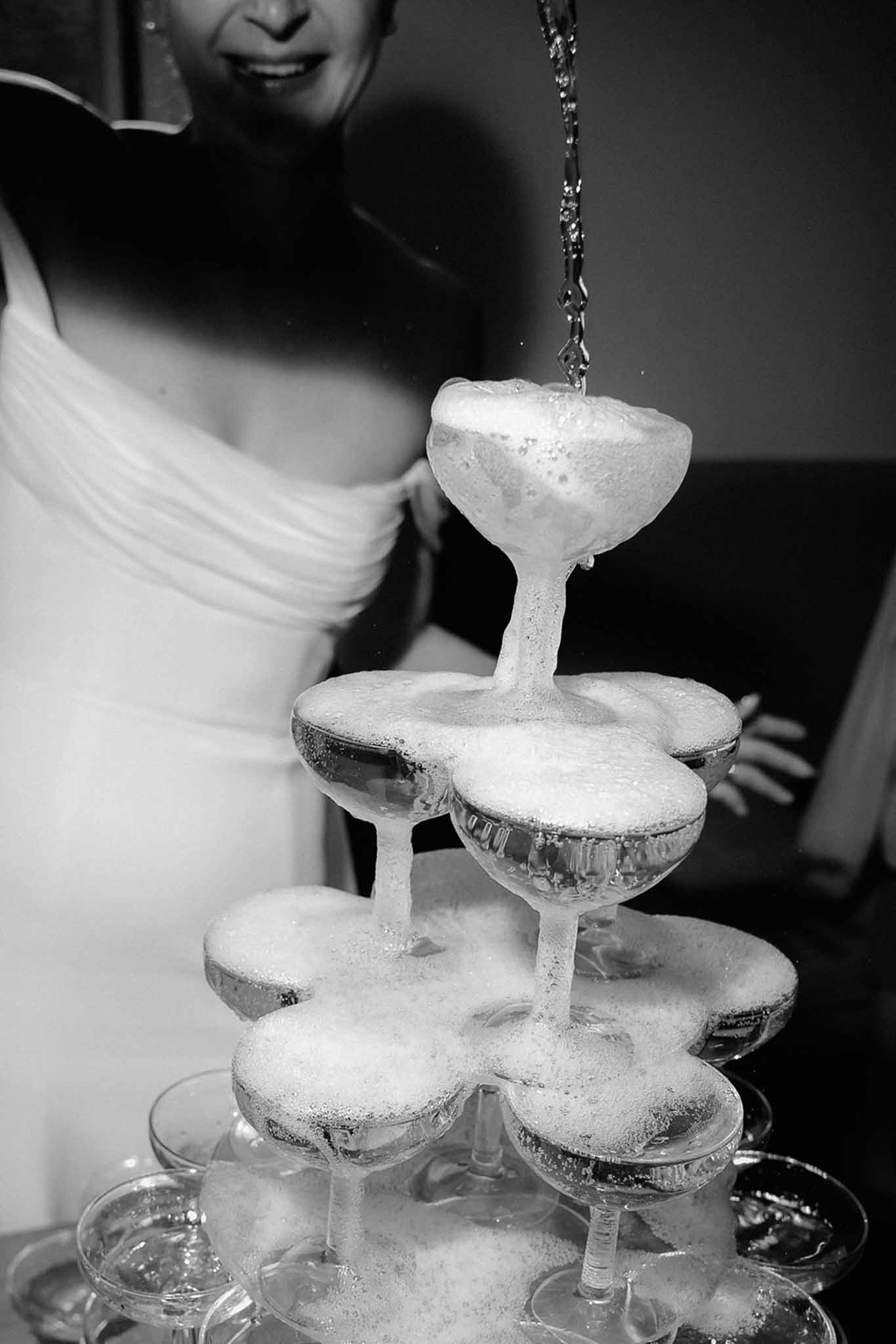 Bride pouring wine into champagne glass tower at Mariage Dime de Giverny reception