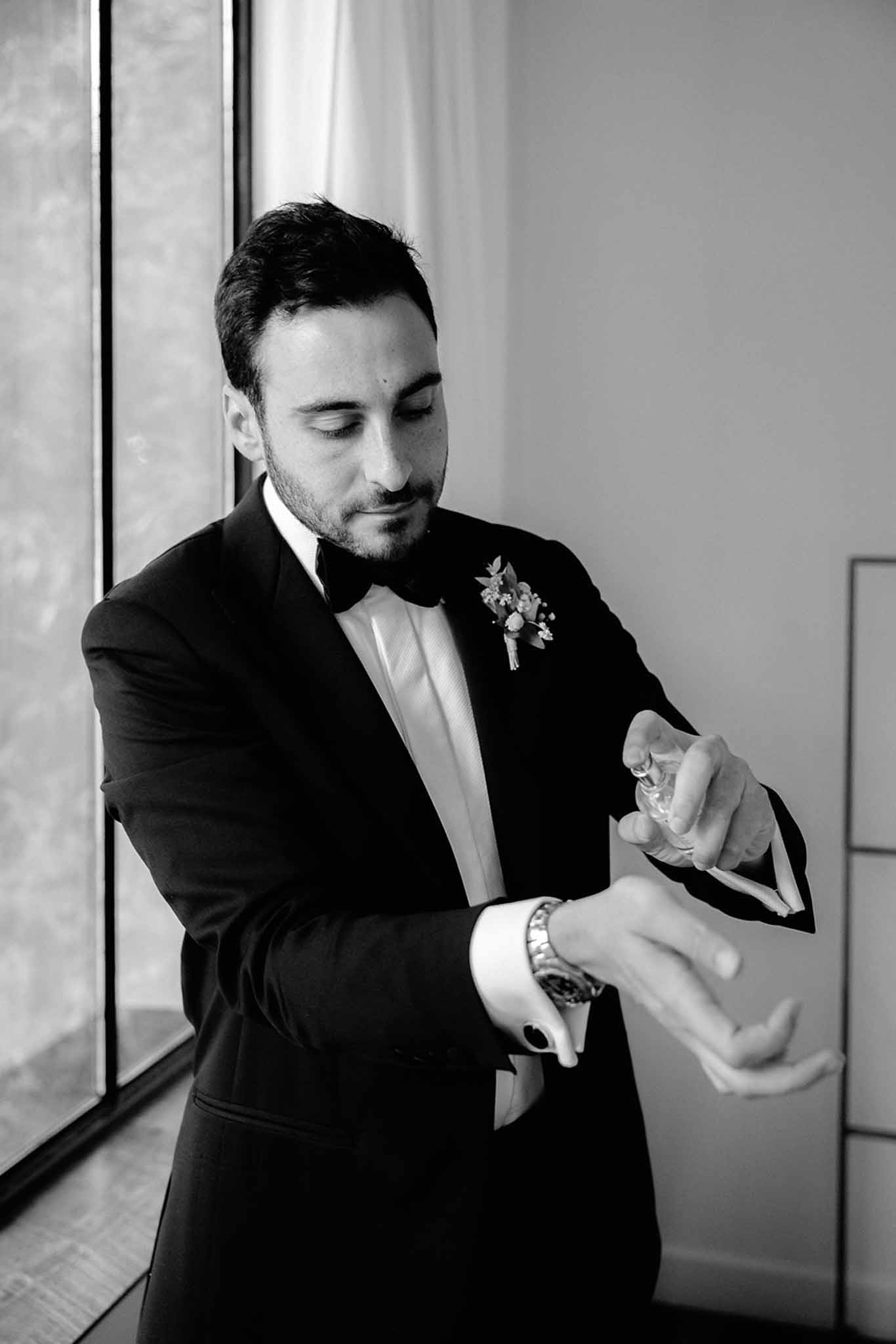 Groom spraying perfume while getting ready, black and white photograph at Dîme de Giverny