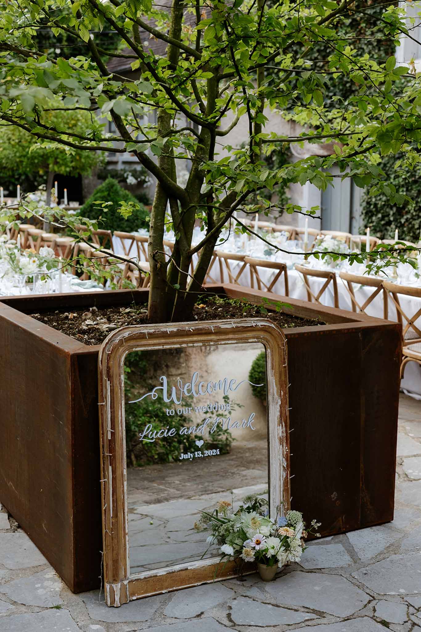 Vintage mirror welcome sign reading wedding names and date beneath a mature tree