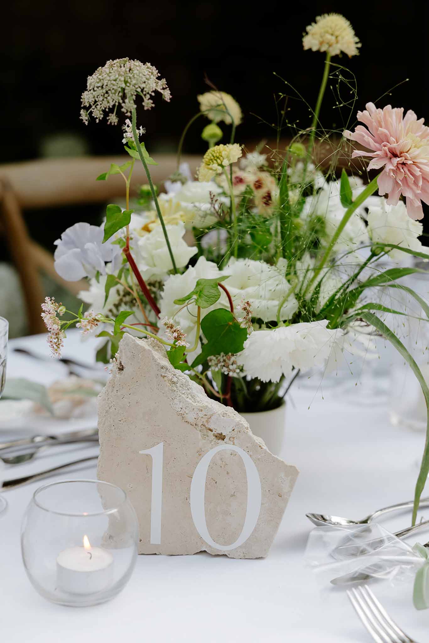 Reception centerpiece with wildflower arrangement, concrete table number, and tea light candle