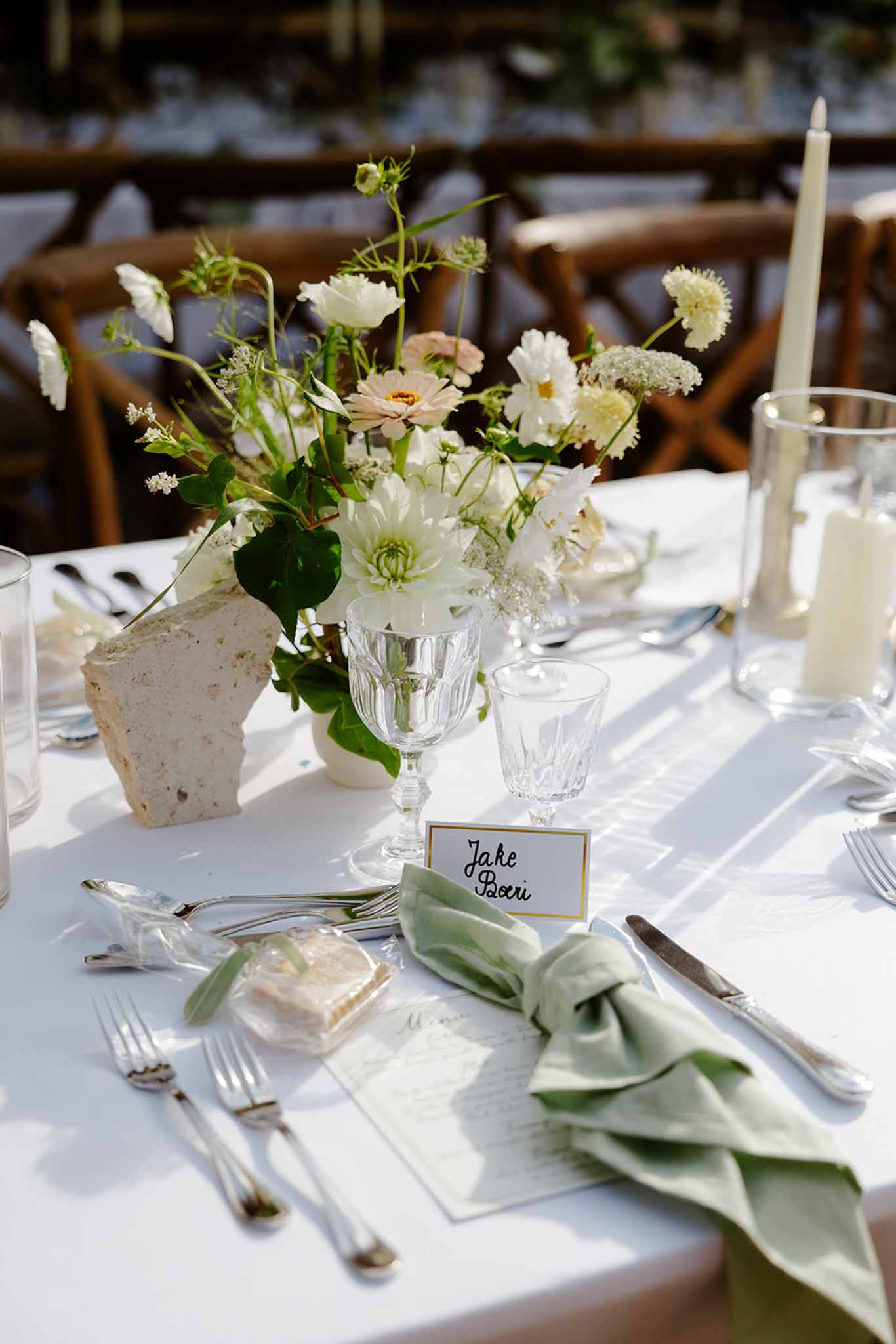 White flower centrepiece with menu card and guest name card on reception table at Mariage Dime de Giverny