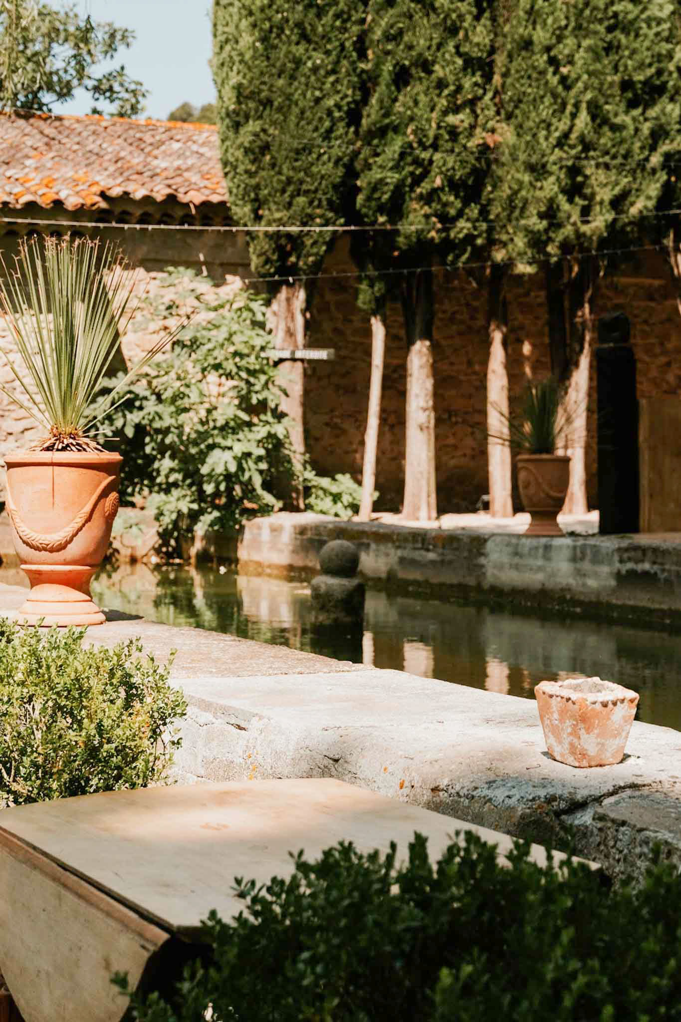 Provencal courtyard with rectangular reflecting pool, terracotta Anduze urns, and stone arcade