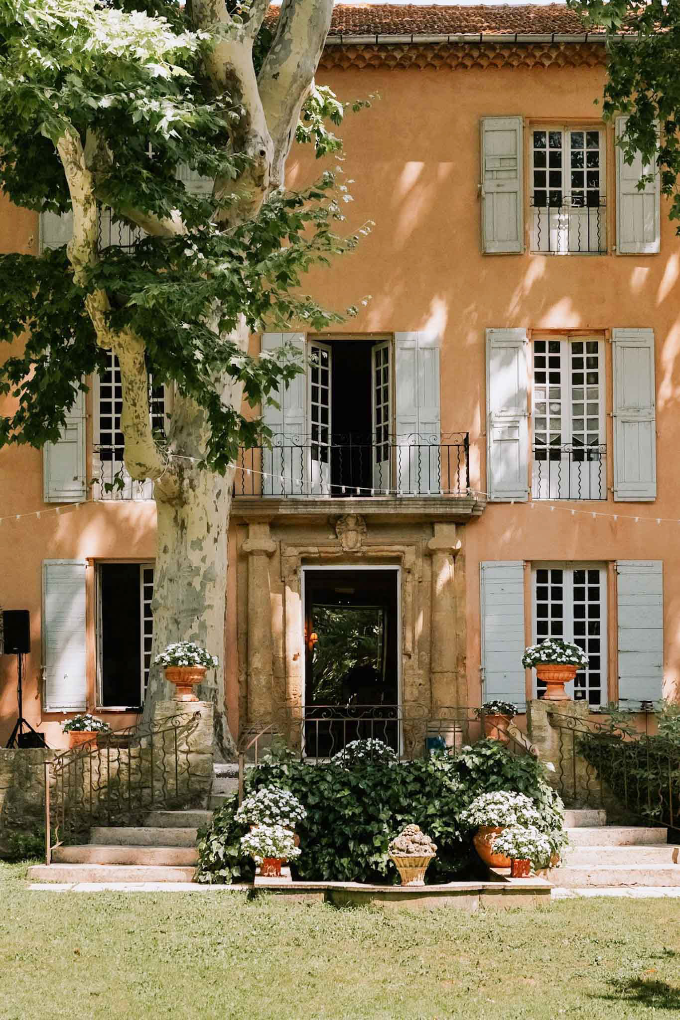 Terracotta-orange Provencal bastide with grey-blue shutters carved doorway fairy lights and urn planters
