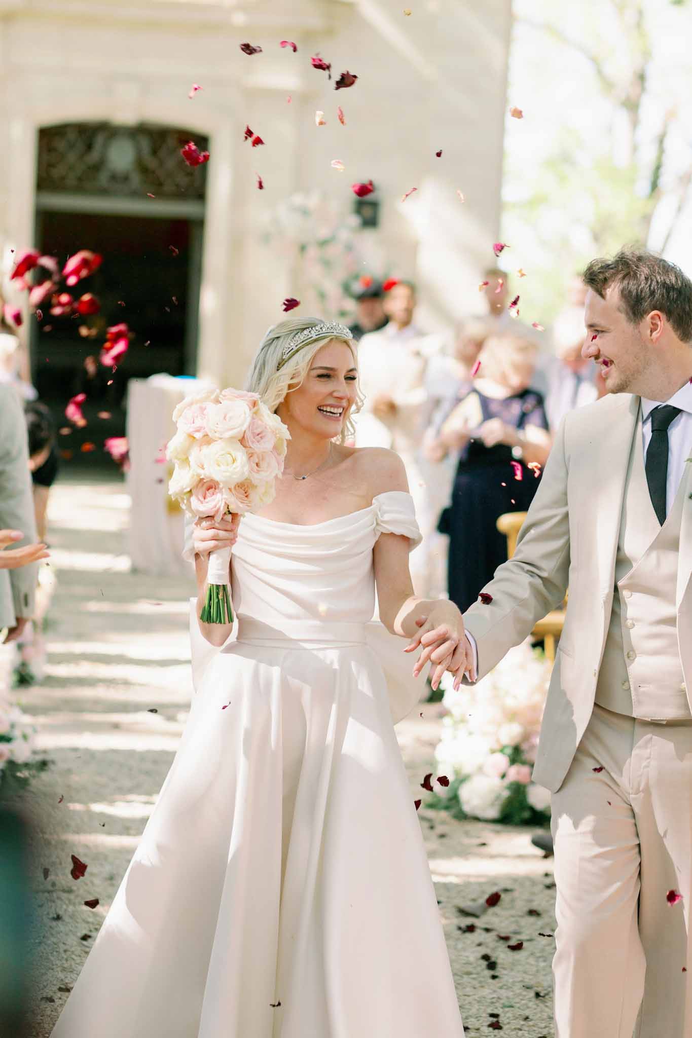 Bride and groom walking through guests throwing red and burgundy rose petals