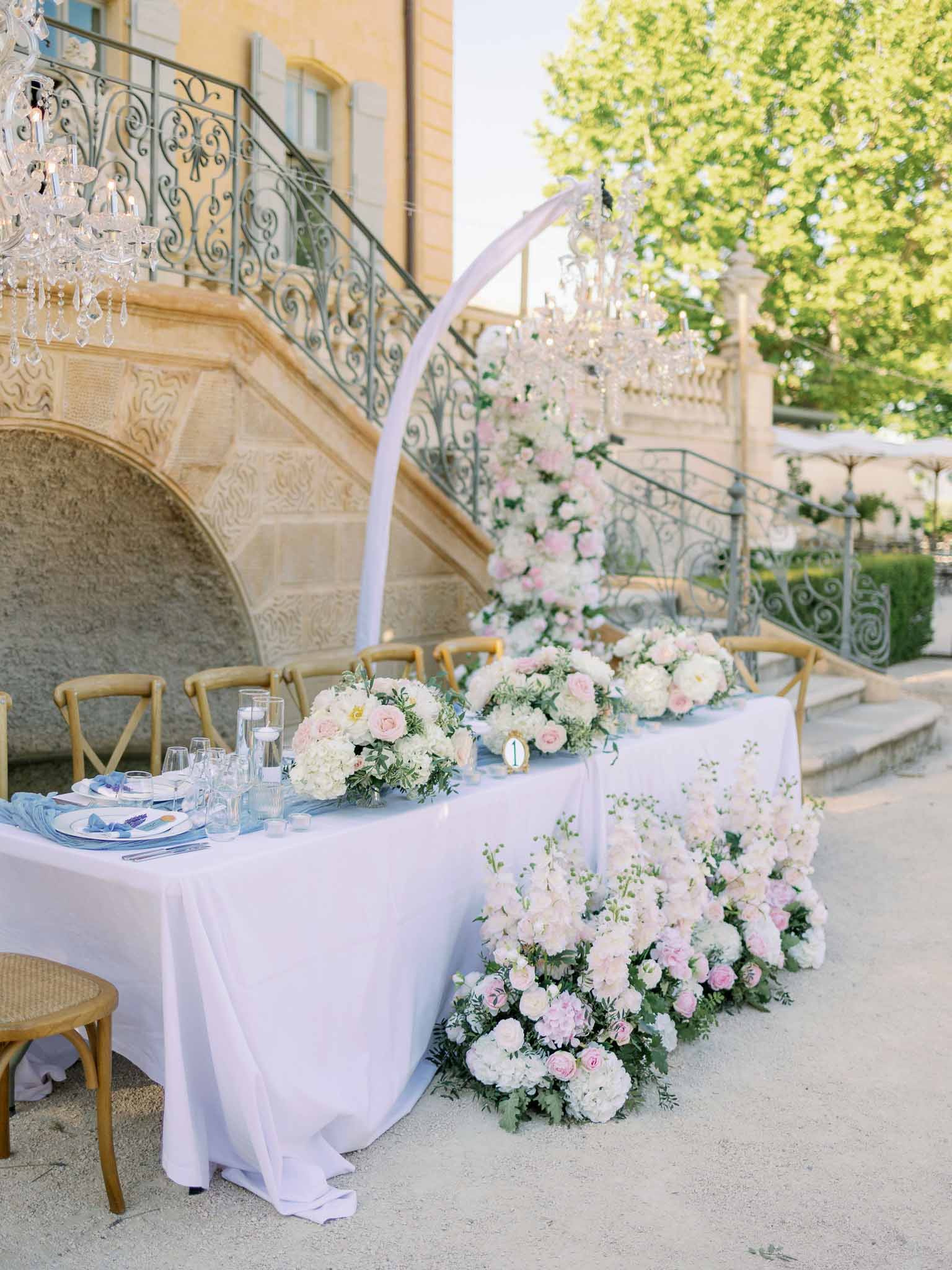 Principal reception table with white floral centerpieces under chandelier at venue