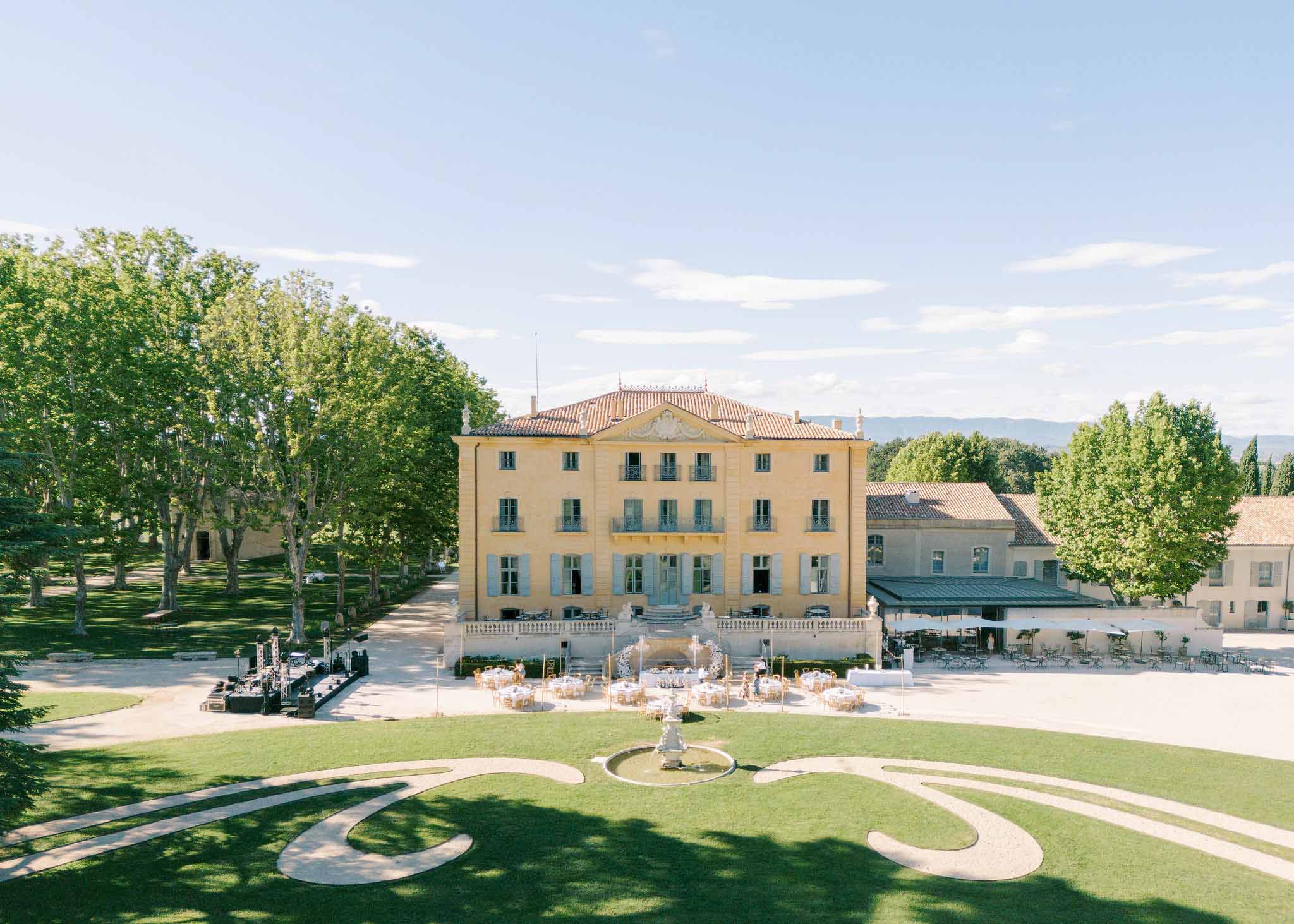 Aerial view of reception with pink-linen round tables and white umbrellas at neoclassical villa