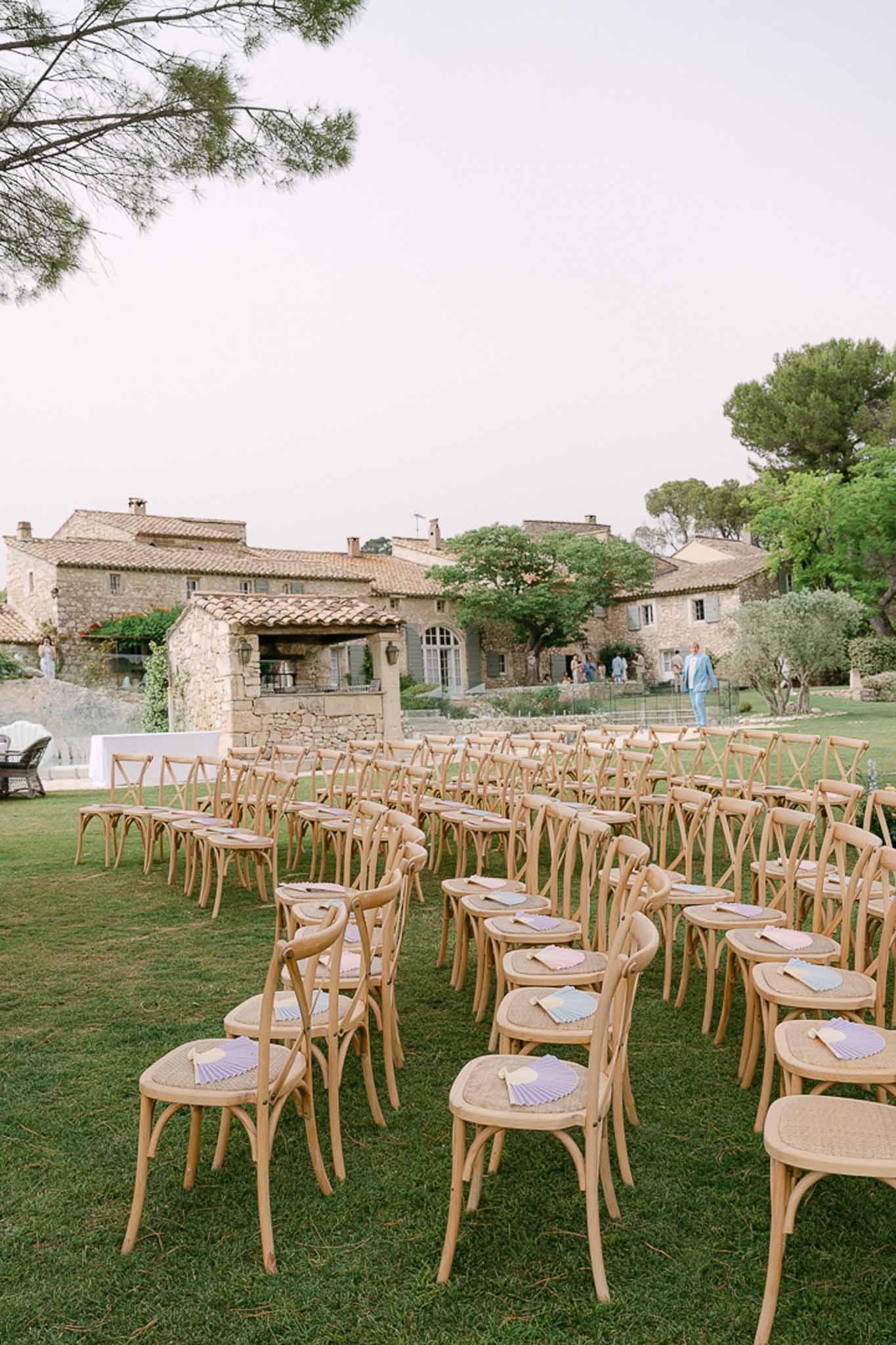 Tuscan stone villa with ceremony chairs on lawn, terracotta roofs, and climbing greenery