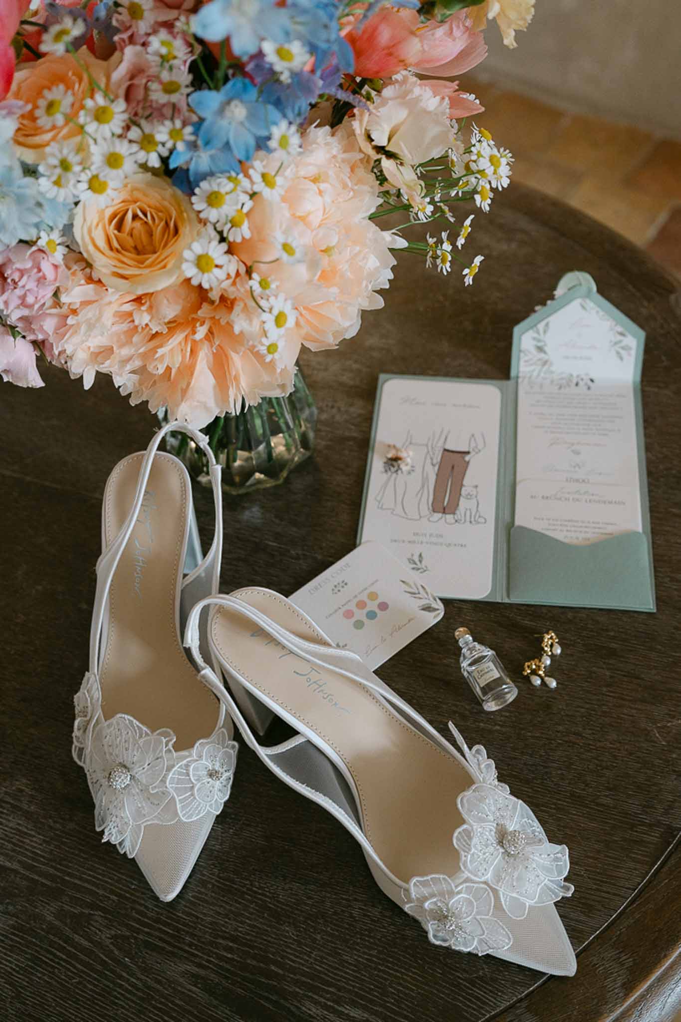 Wedding flat lay with shoes, rings, stationery in a garden setting