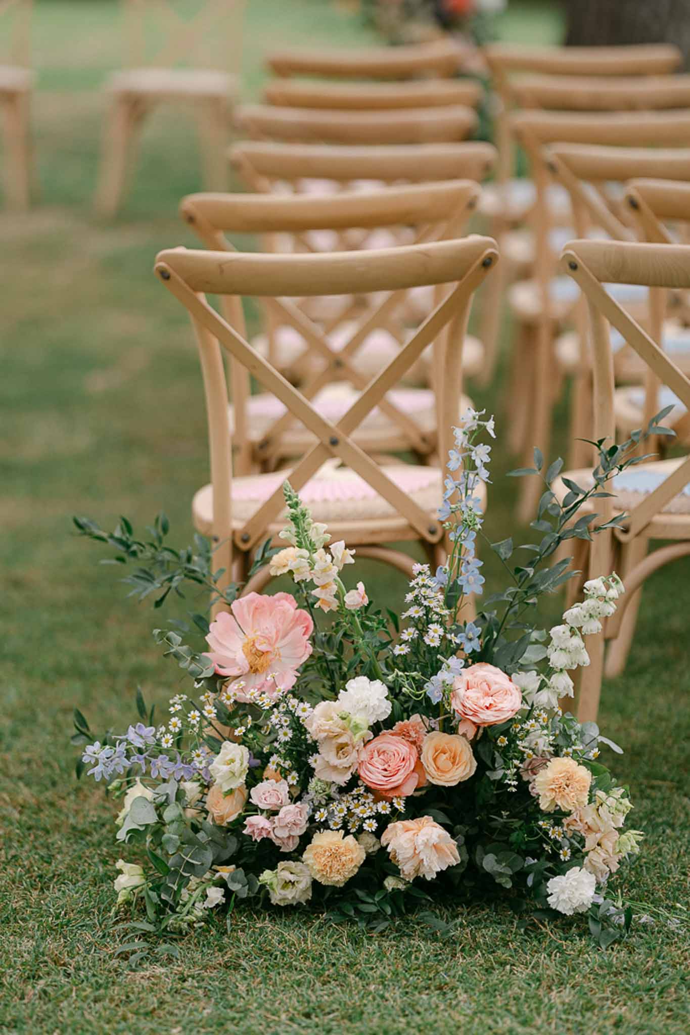 Garden-style floral arrangement of blush roses, coral blooms, and dusty blue delphinium