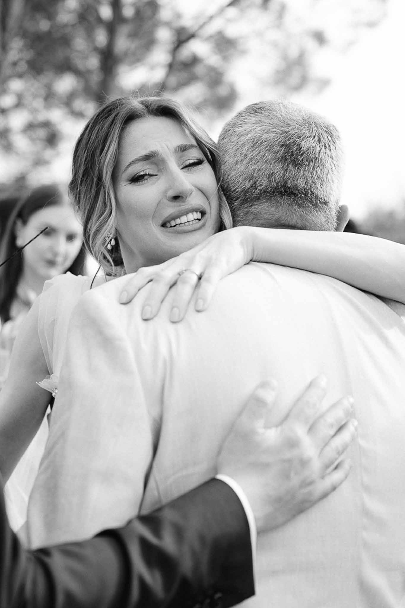 Black and white photo of bride embracing her father during wedding reception